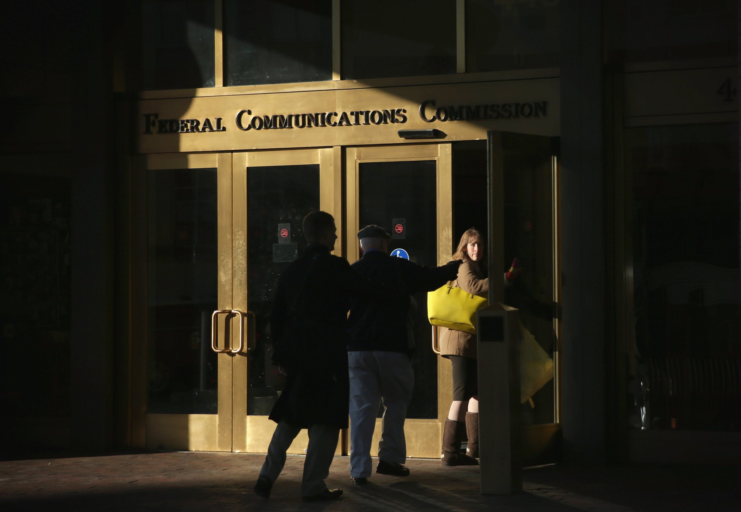 People enter the Federal Communications Commission building December 11, 2014 in Washington, D.C. The commission held its monthly meeting as activists held a rally outside to call for net neutrality.