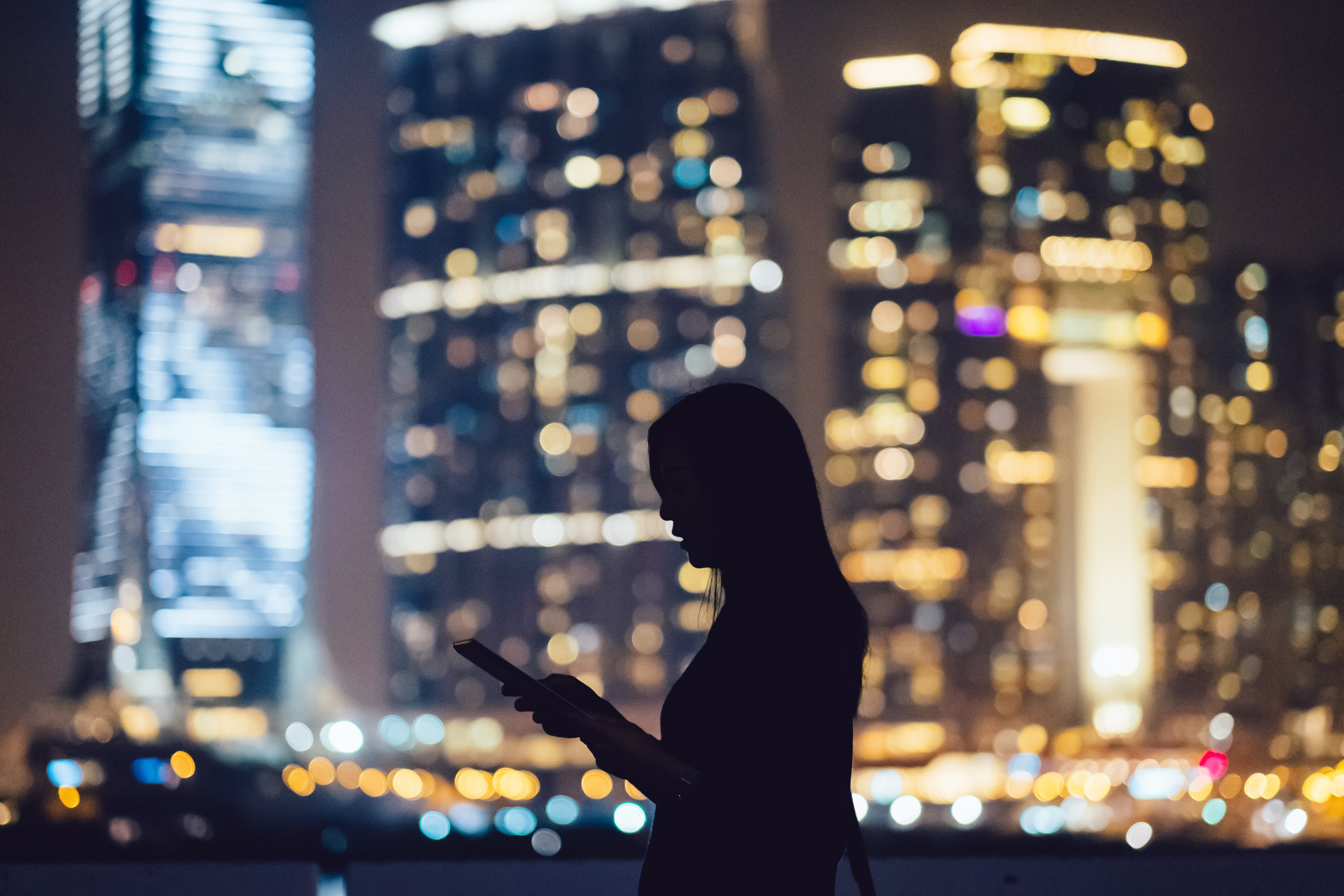 Silhouette of woman with digital tablet in city