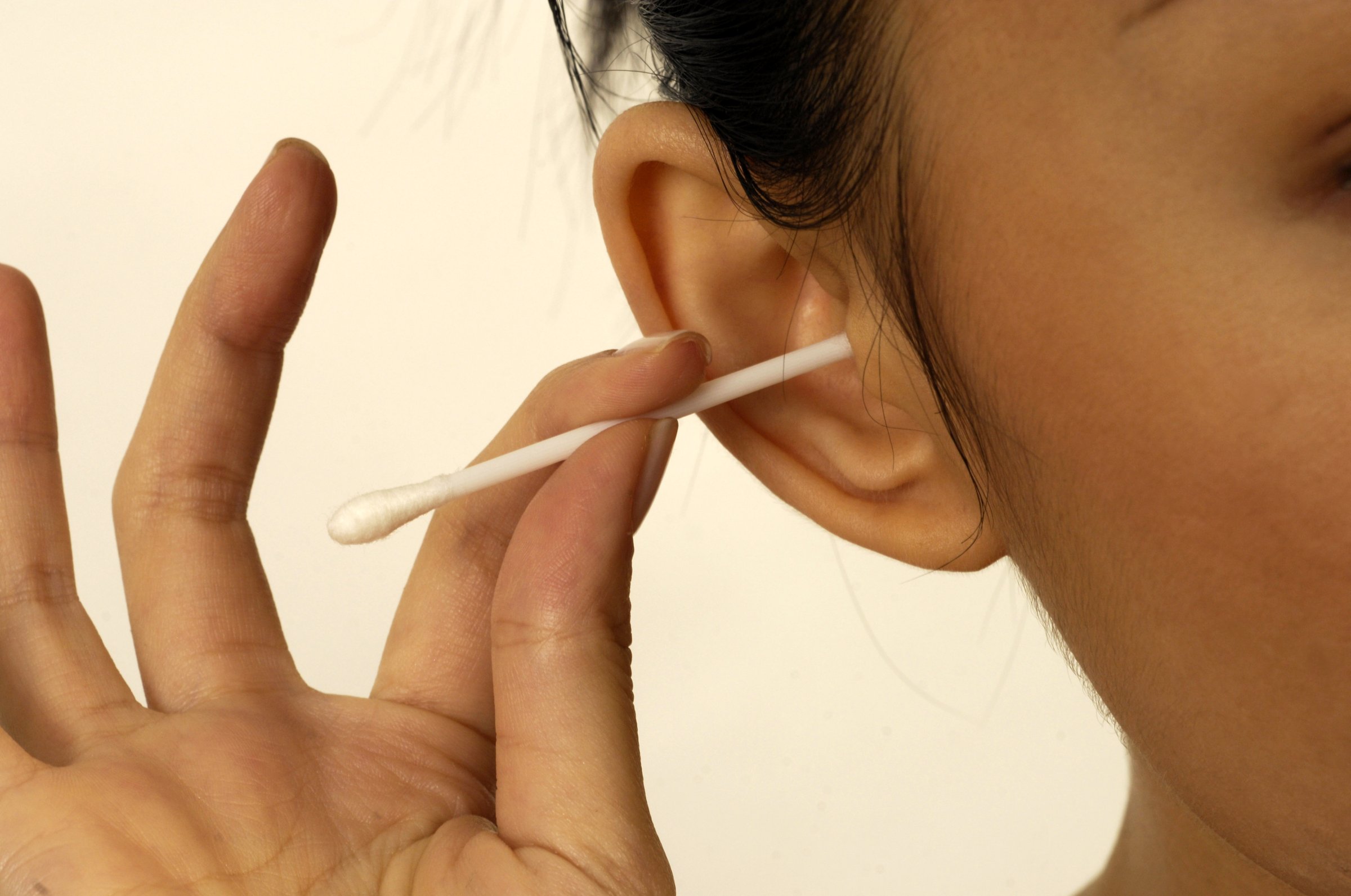 Close-up of woman cleaning her ear with cotton bud