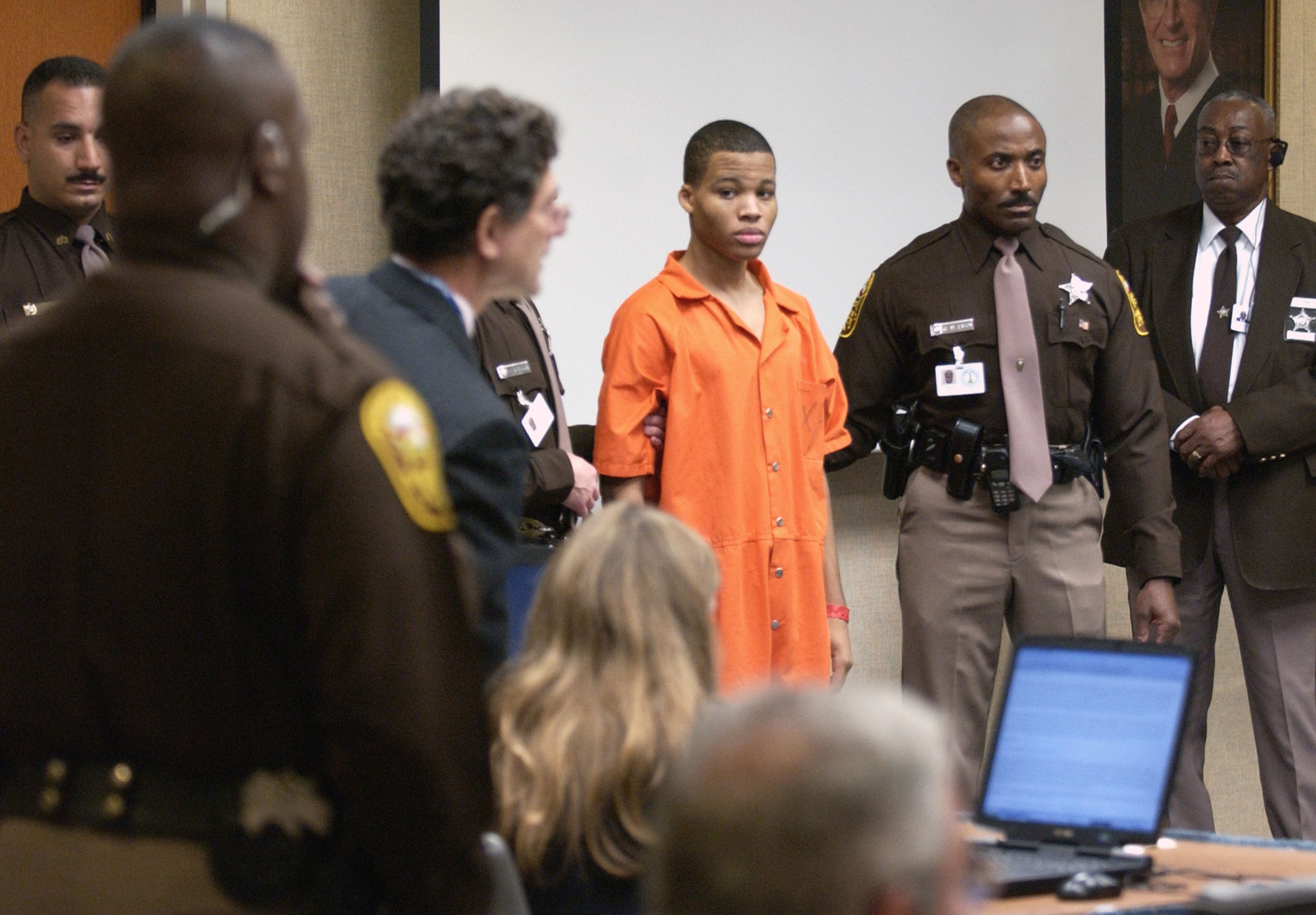 Sniper suspect Lee Boyd Malvo (C) is escorted by deputies as he is brought into court to be identified by a witness during the murder trial in courtroom 10 at the Virginia Beach Circuit Court October 22, 2003 in Virginia Beach, Virginia. Muhammad has decided not to represent himself in court and to turn his defense back to his attorneys. (Photograph by Davis Turner—Getty/Pool)
