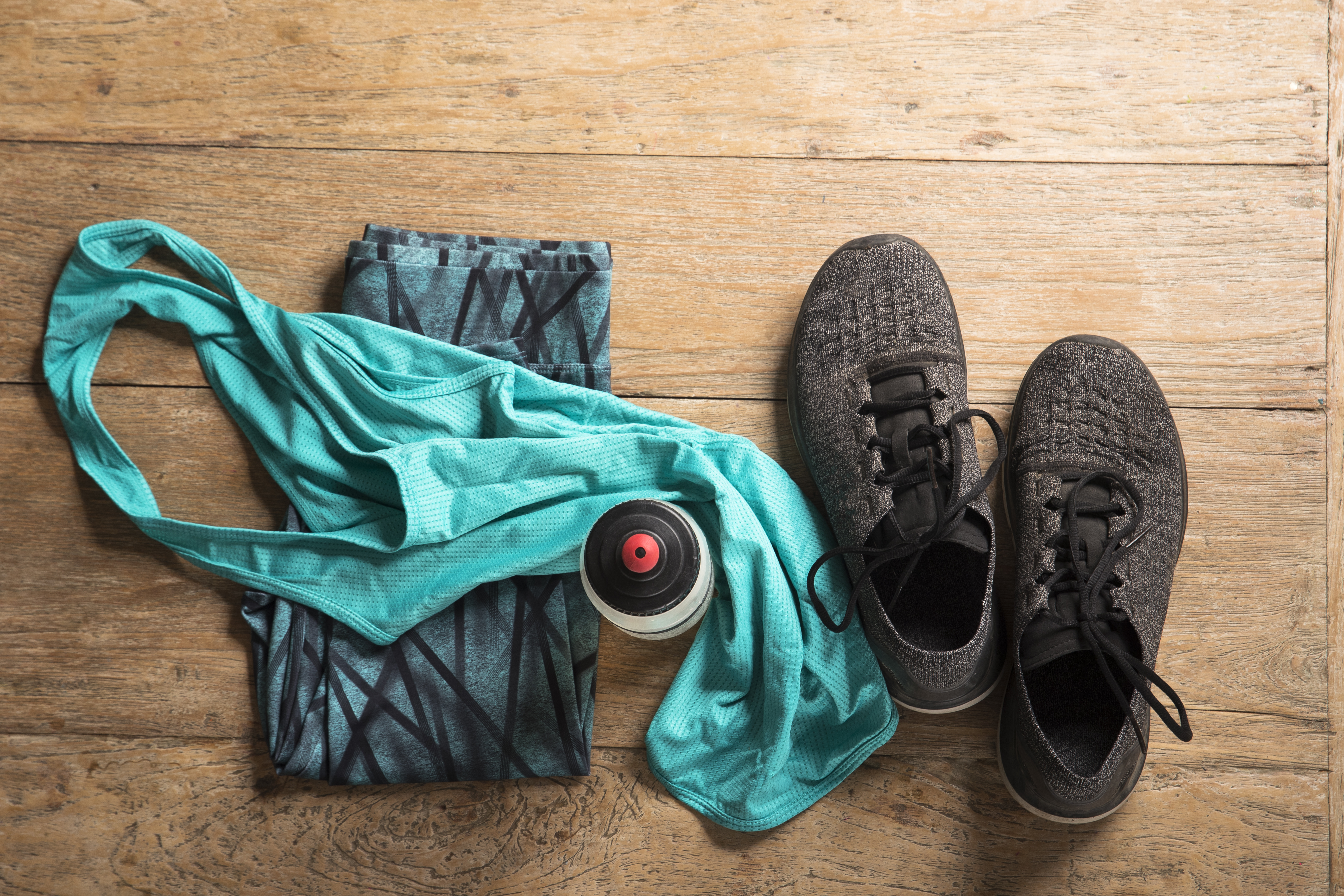 Flat Lay image of sports clothes and shoes on a wooden floor.