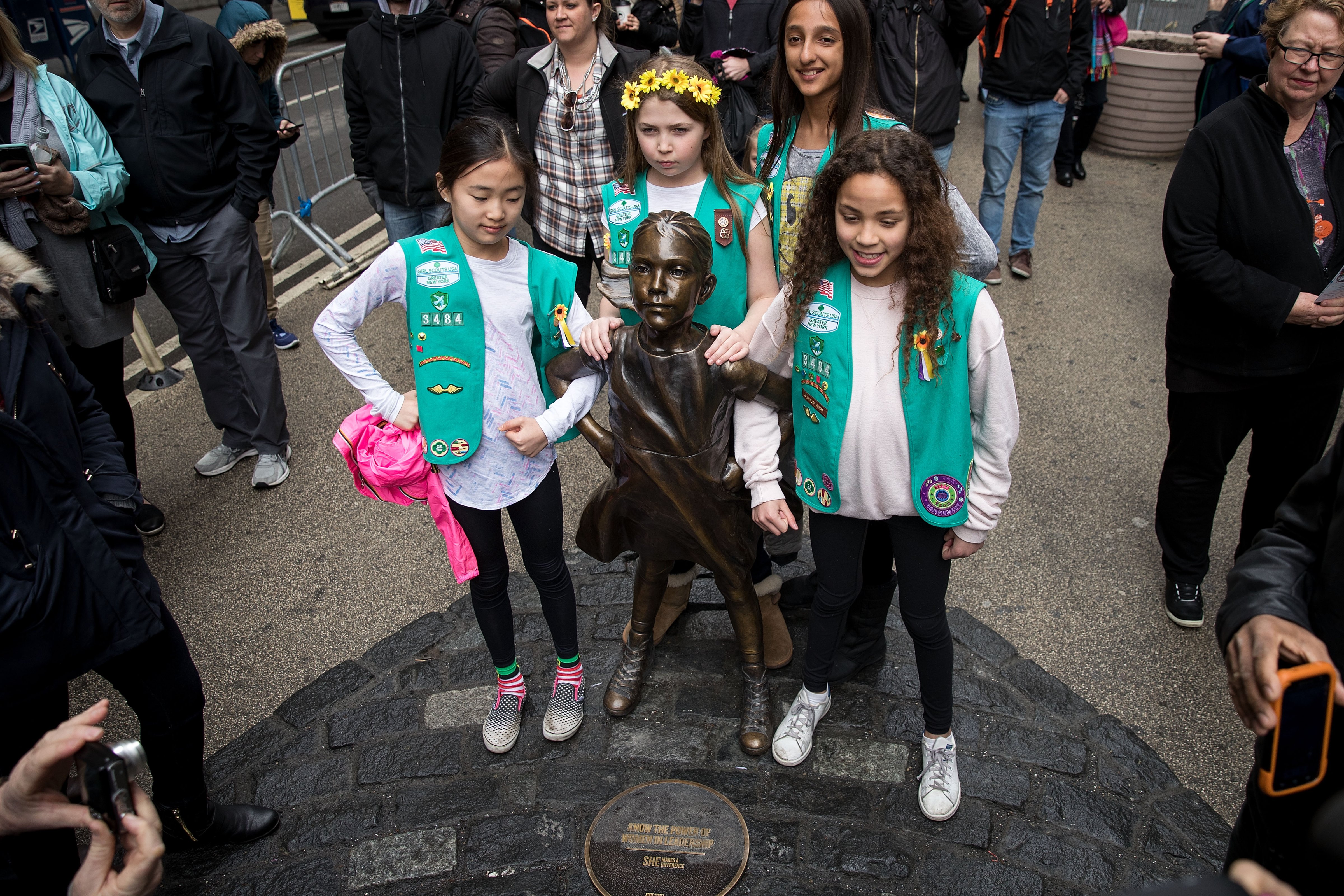 Young members of Girl Scout troop 3484 pose for photos with the 'Fearless Girl' statue, March 27, 2017 in New York City. (Photograph by Drew Angerer—Getty)