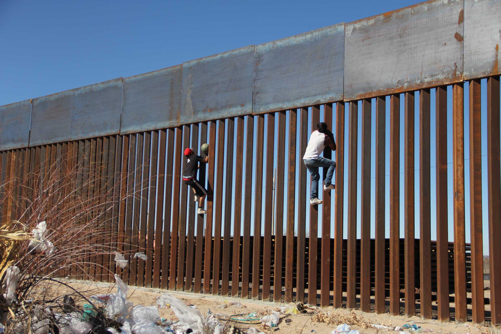 Boys climb the Mexico-US border wall on the Mexico side.