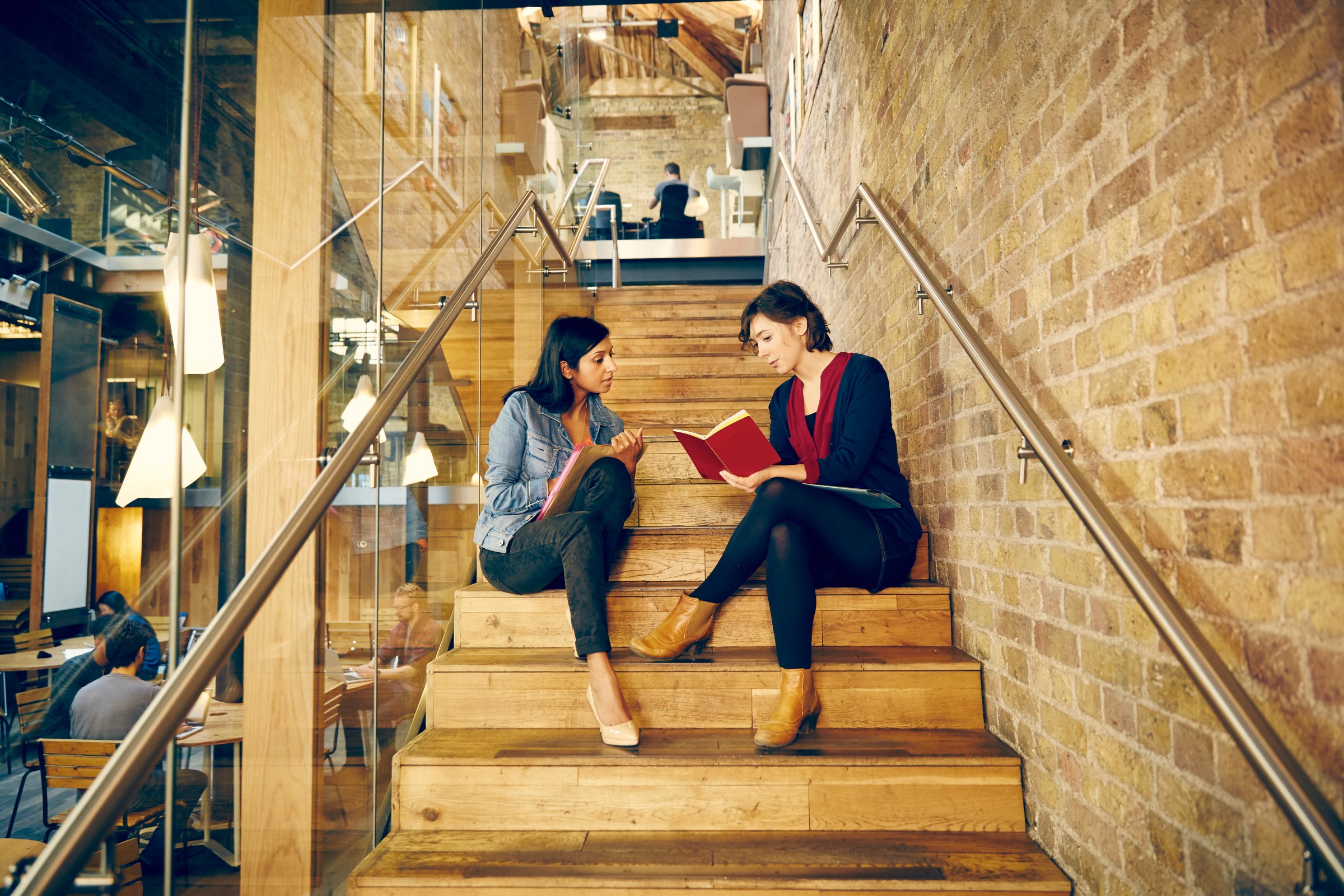 Two colleagues discuss work on stairs of office