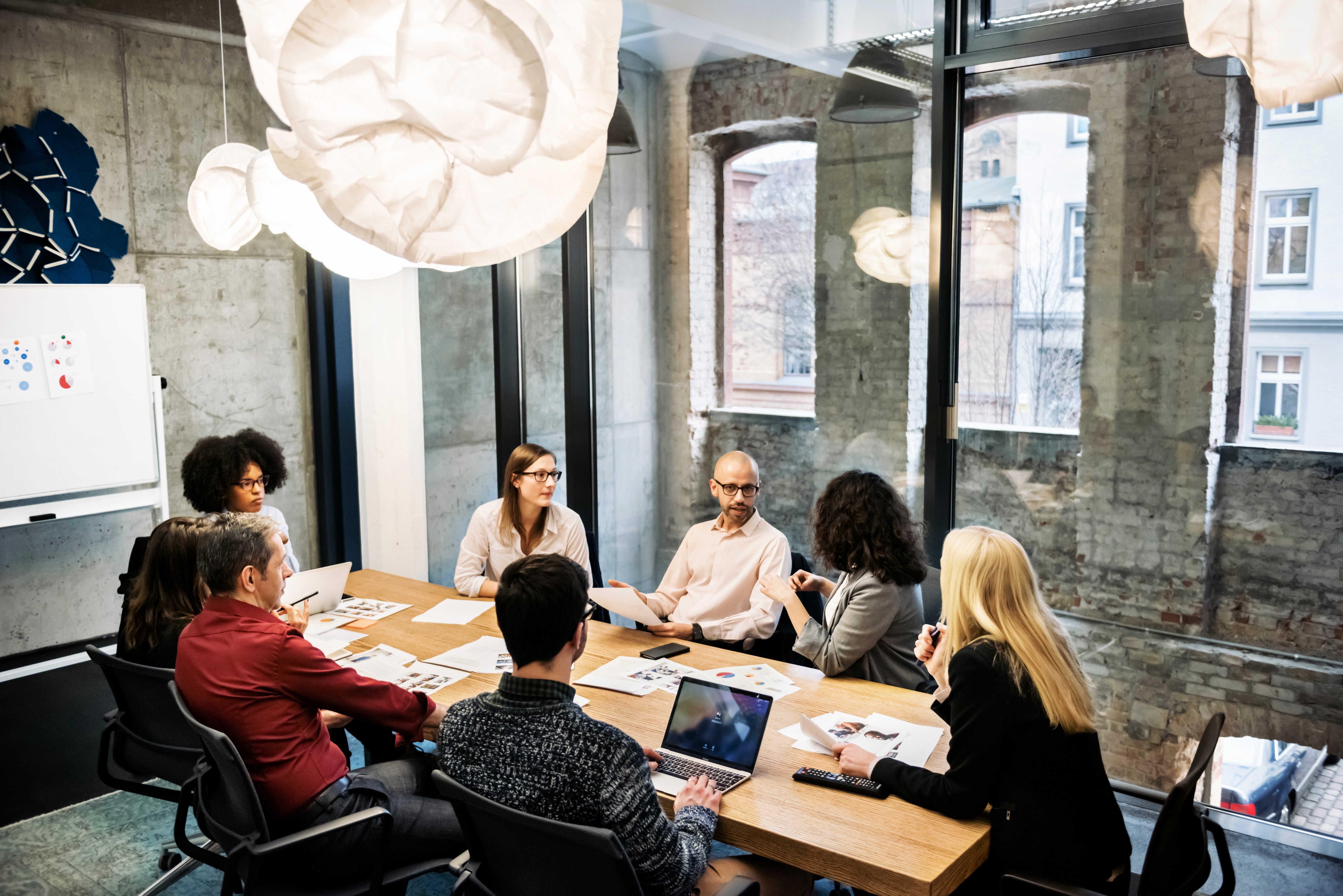 A group of young people, male and female, of different ethnicities are sitting in a bright modern office room. They are discussing something during a business meeting. There are documents and laptops on the table. (Getty Images)