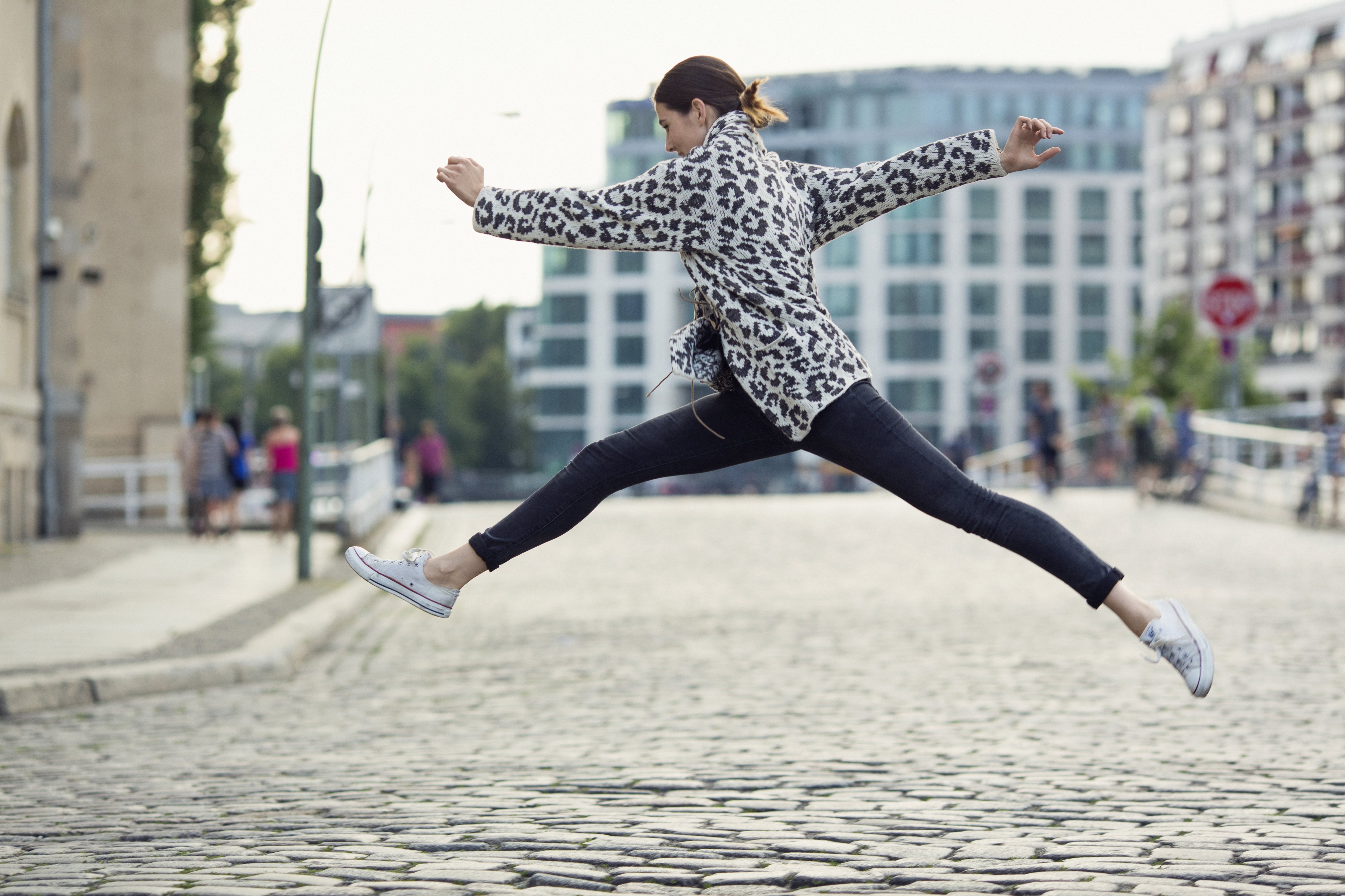woman making a big jump in a sunny city street