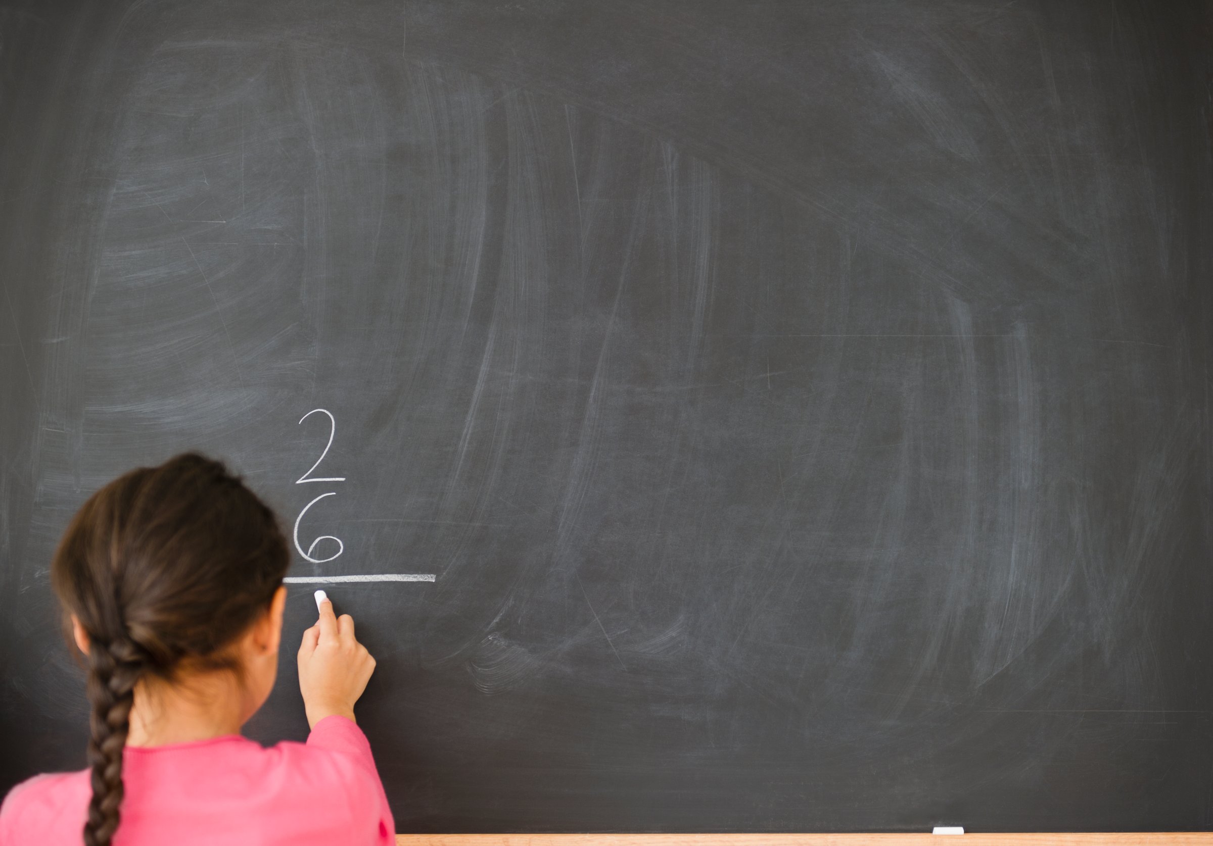 Mixed race girl doing math on blackboard