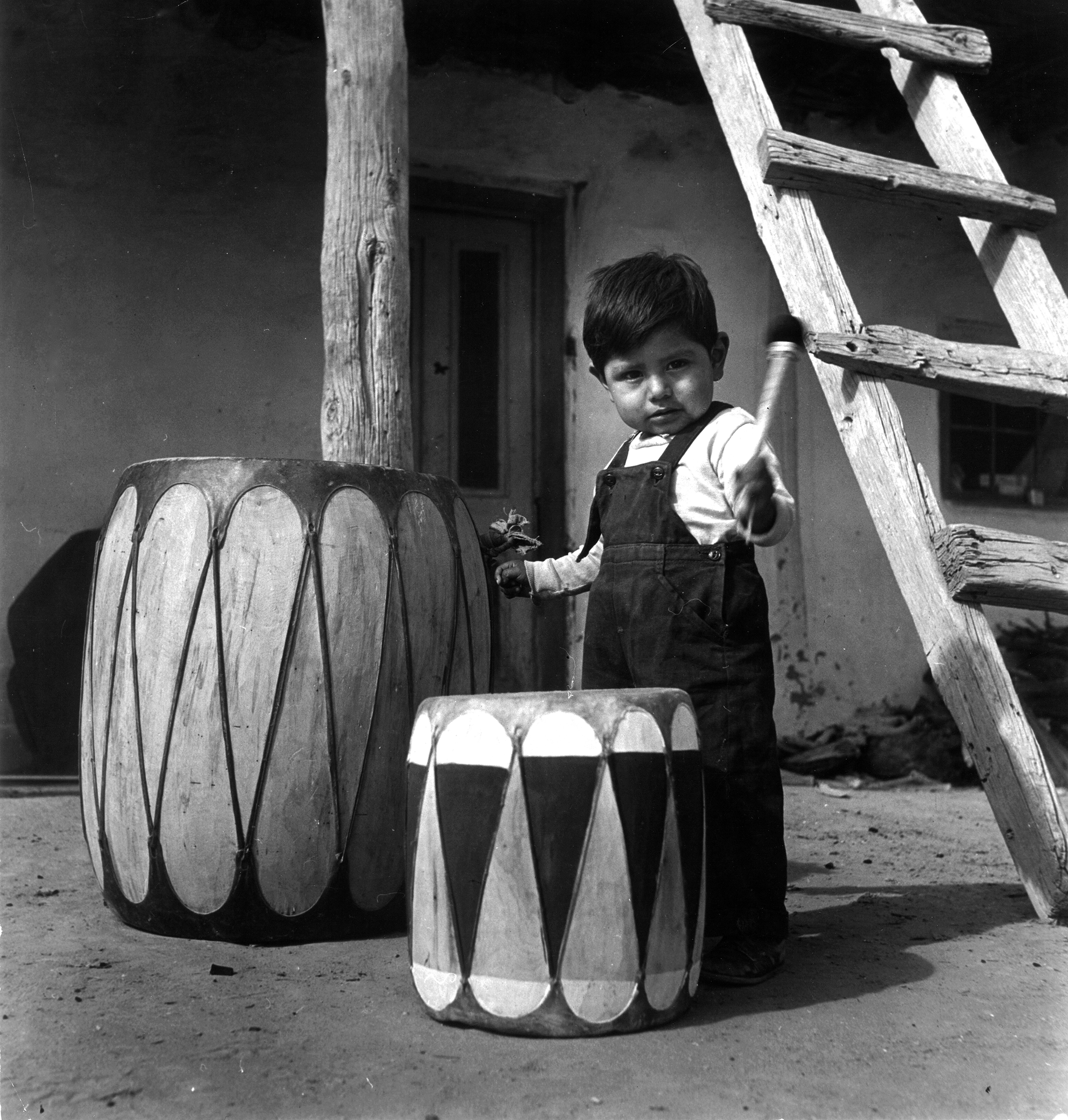 Native American boy of the Chochiti tribe playing drum outside his home, Sante Fe, New Mexico in 1947.