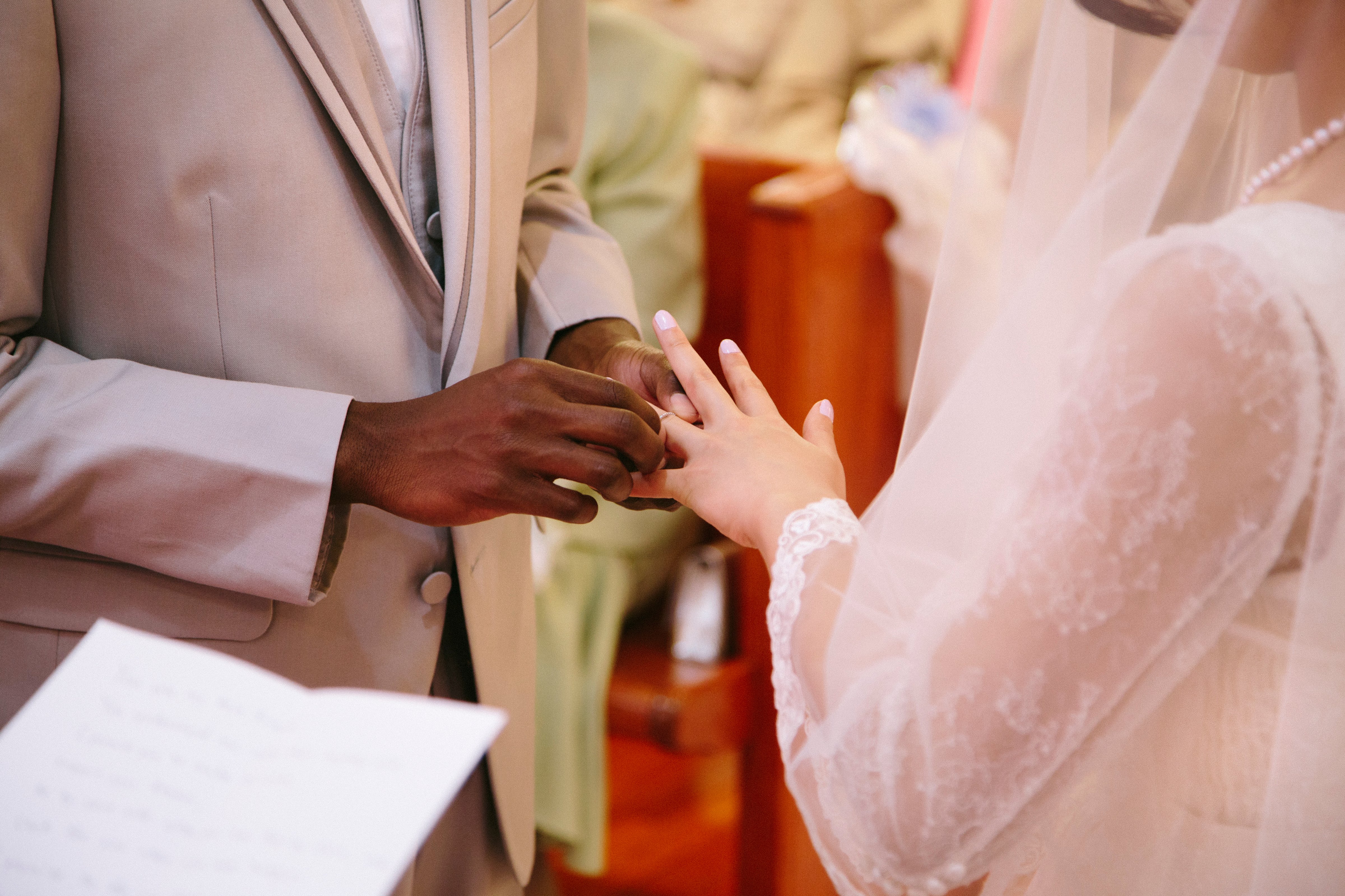 Cropped view of bridegroom putting ring on brides finger at wedding ceremony