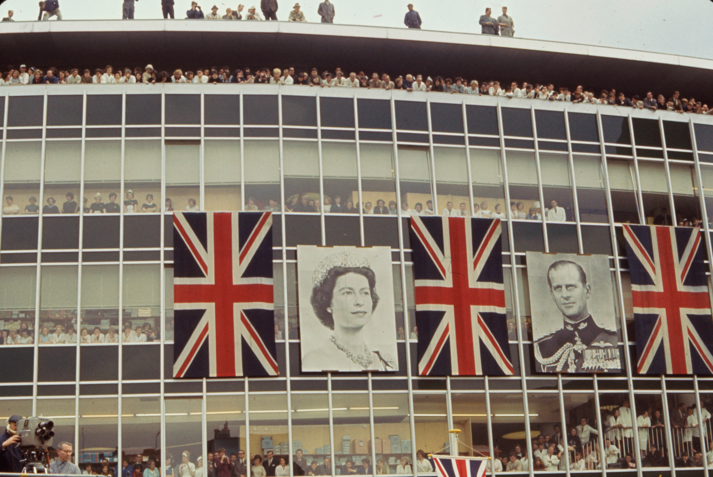 Crowds peer out windows and balconies to catch a glimpse of Queen Elizabeth II and Prince Philip, Bonn, Germany, May 1965.