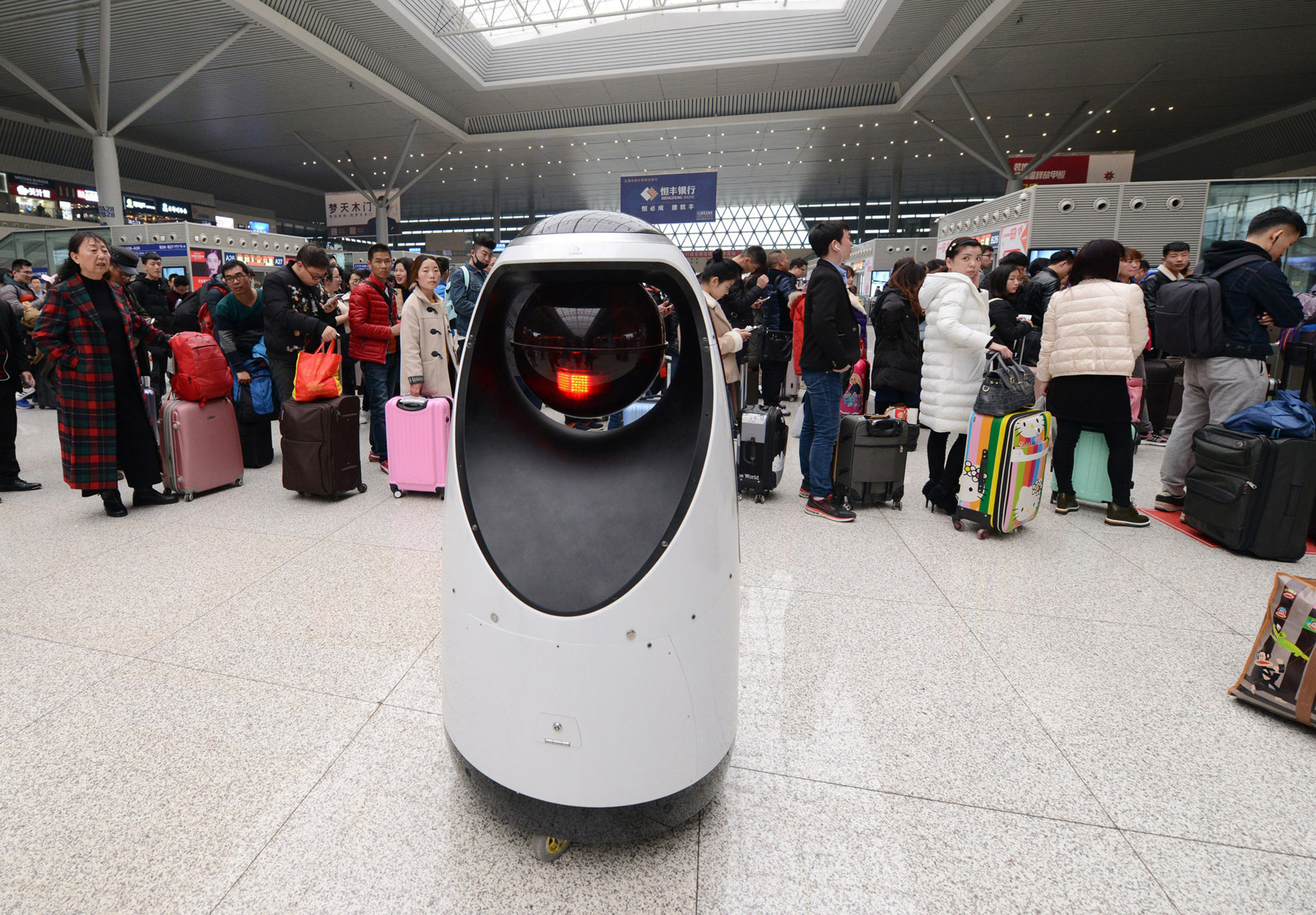 Passengers look at a police robot at Zhengzhou East Railway Station on February 15, 2017 in Zhengzhou, Henan Province of China. (Zhang Tao—VCG/Getty Images)