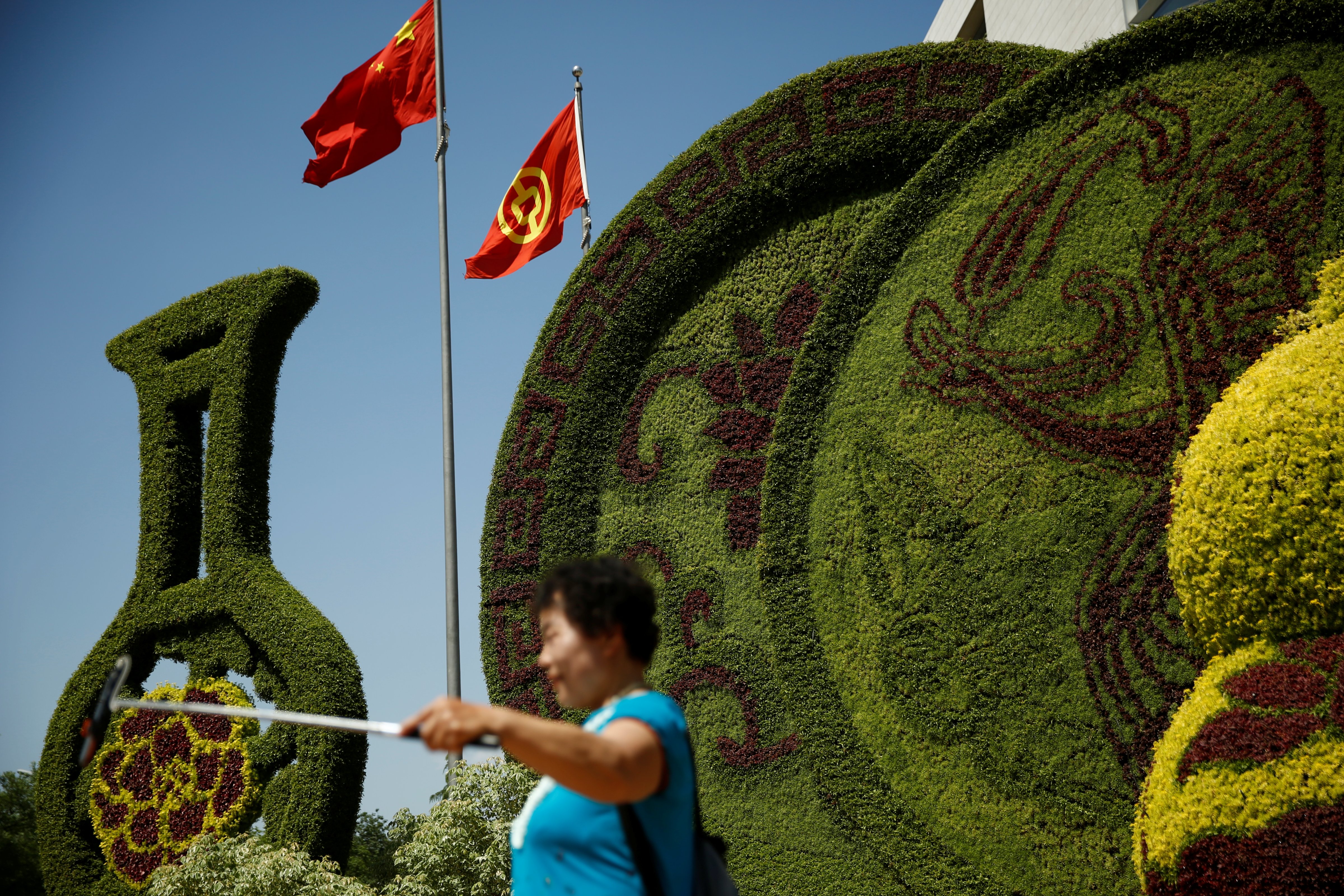 A woman takes pictures in front of a flower display ahead of the Belt and Road Forum in central Beijing, China, May 10, 2017. (Thomas Peter—Reuters)
