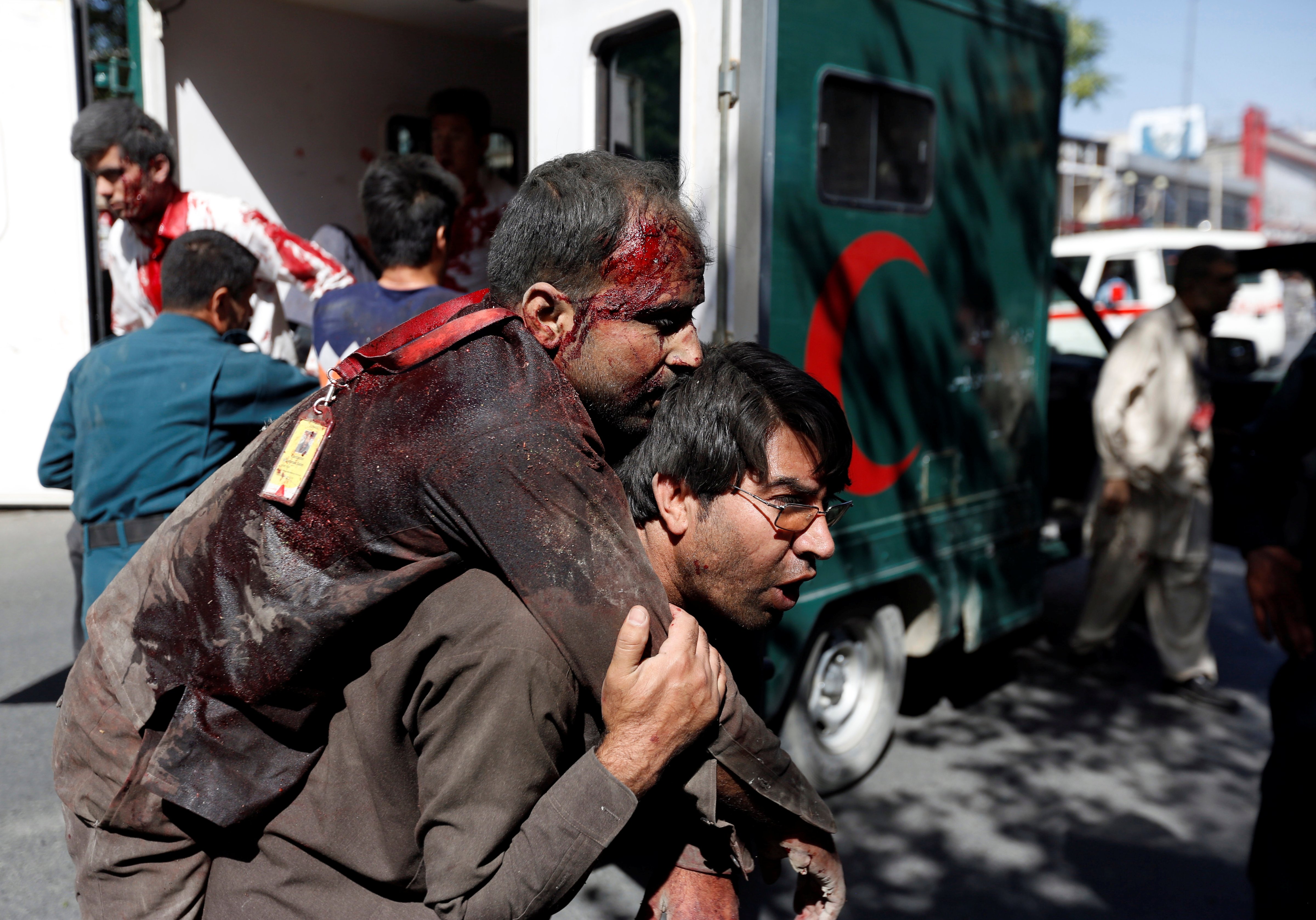 An Afghan man carries an injured man to a hospital after a blast in Kabul, Afghanistan
