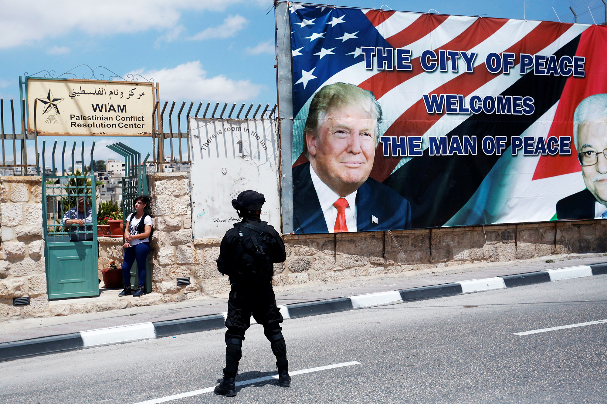 A soldier stands guard over the route as people watch Trump's motorcade carry him back to Jerusalem after his meeting with Abbas in the West Bank city of Bethlehem