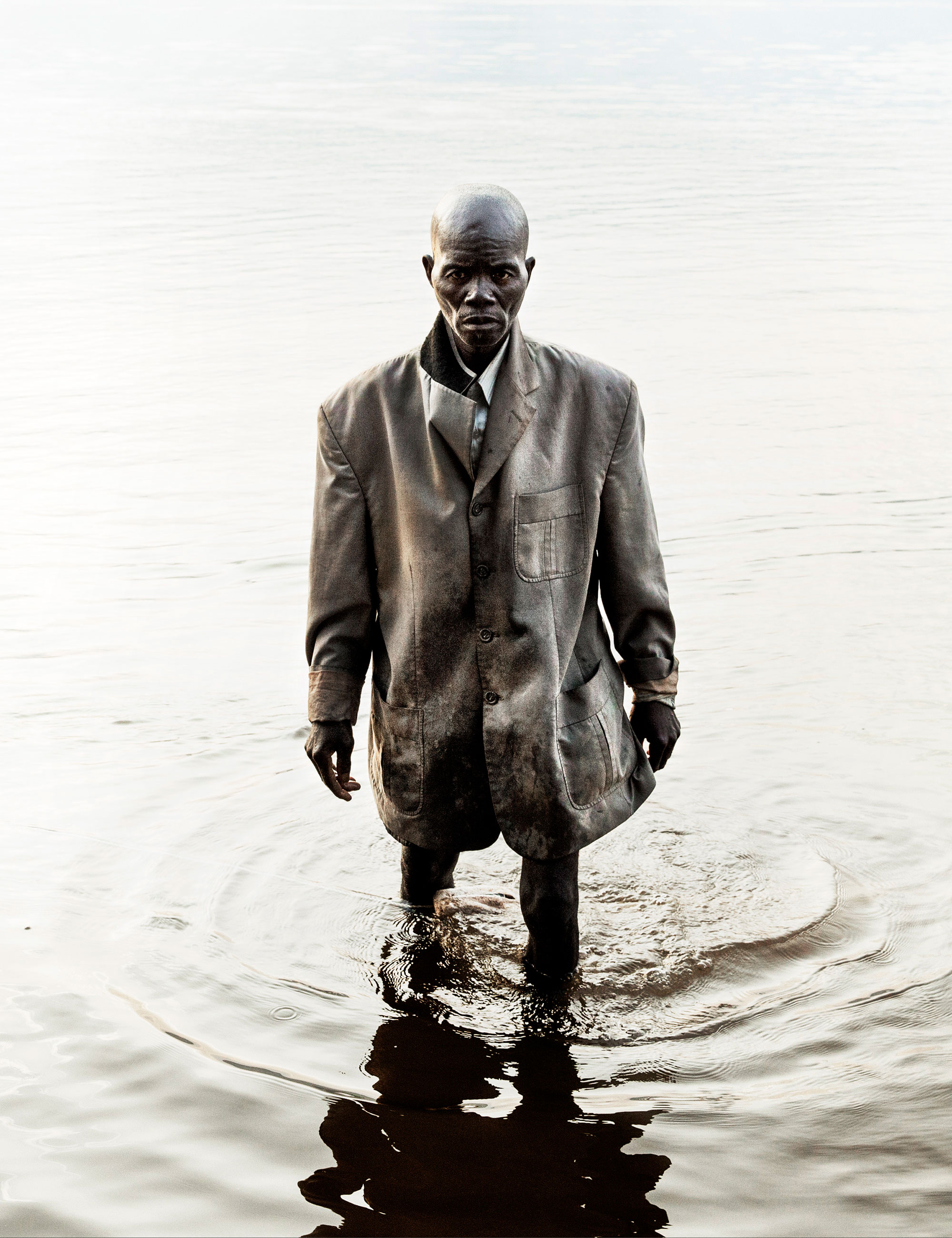 A fisherman dressed for Sunday Mass walks in the UbanguiRiver in the early morning.