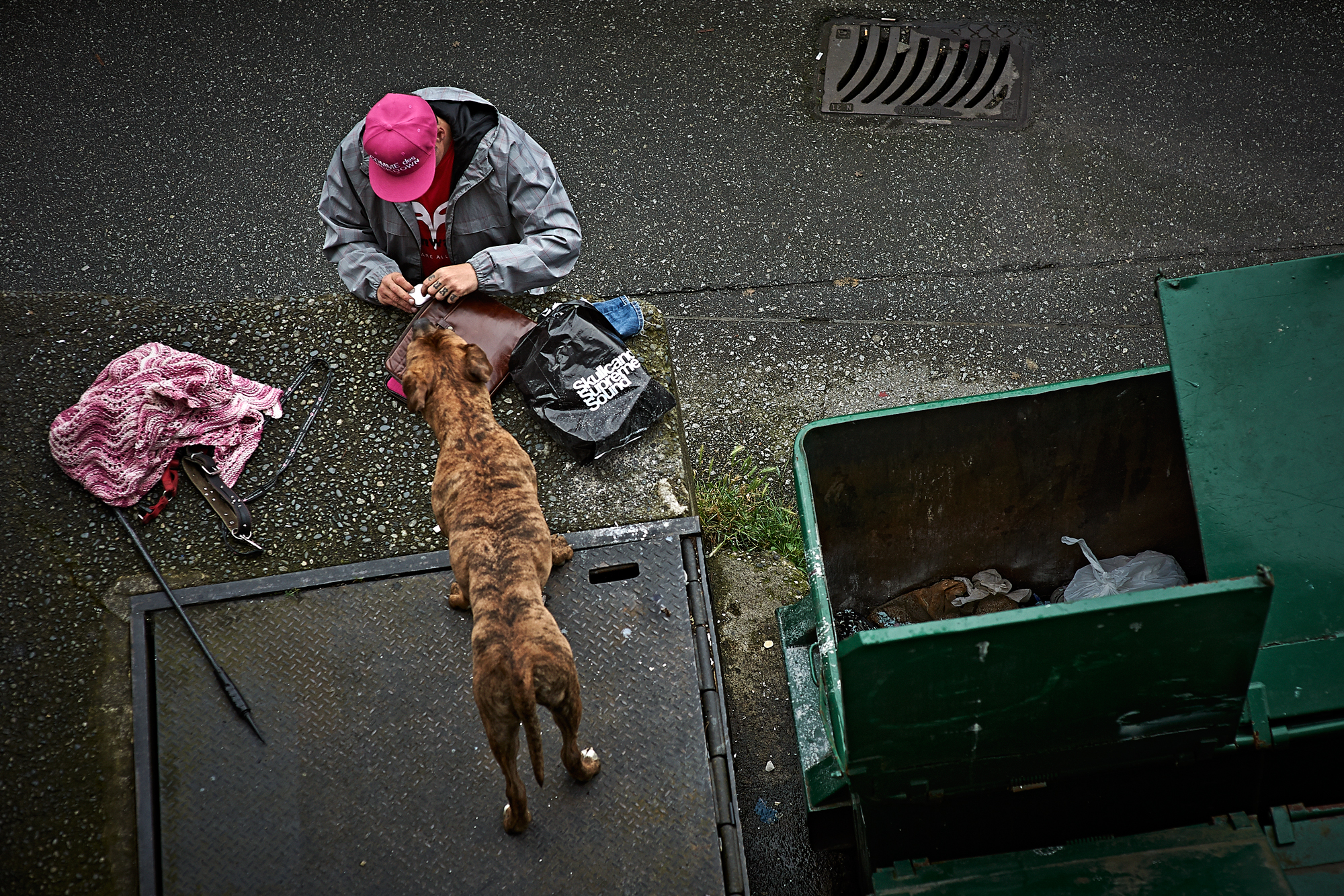 A man searches through discarded items as his dog watches. June, 2014.