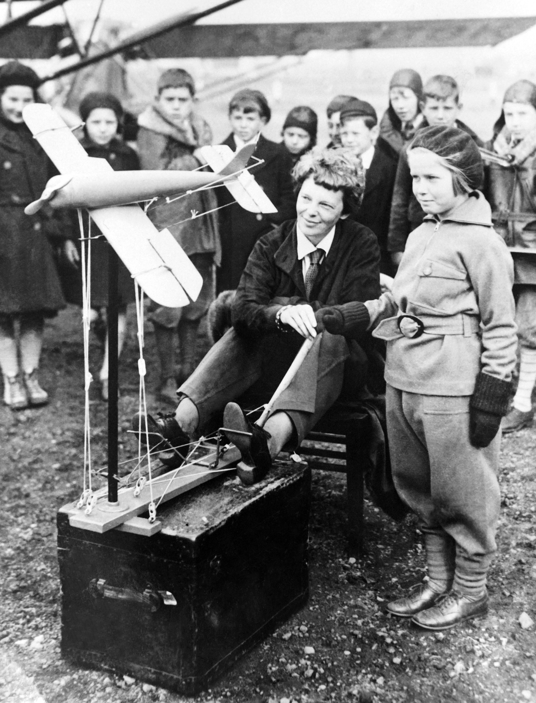 Amelia Earhart explains to children with a reduced model, the operation of the catapult to launch an aircraft on Nov. 28, 1933.
