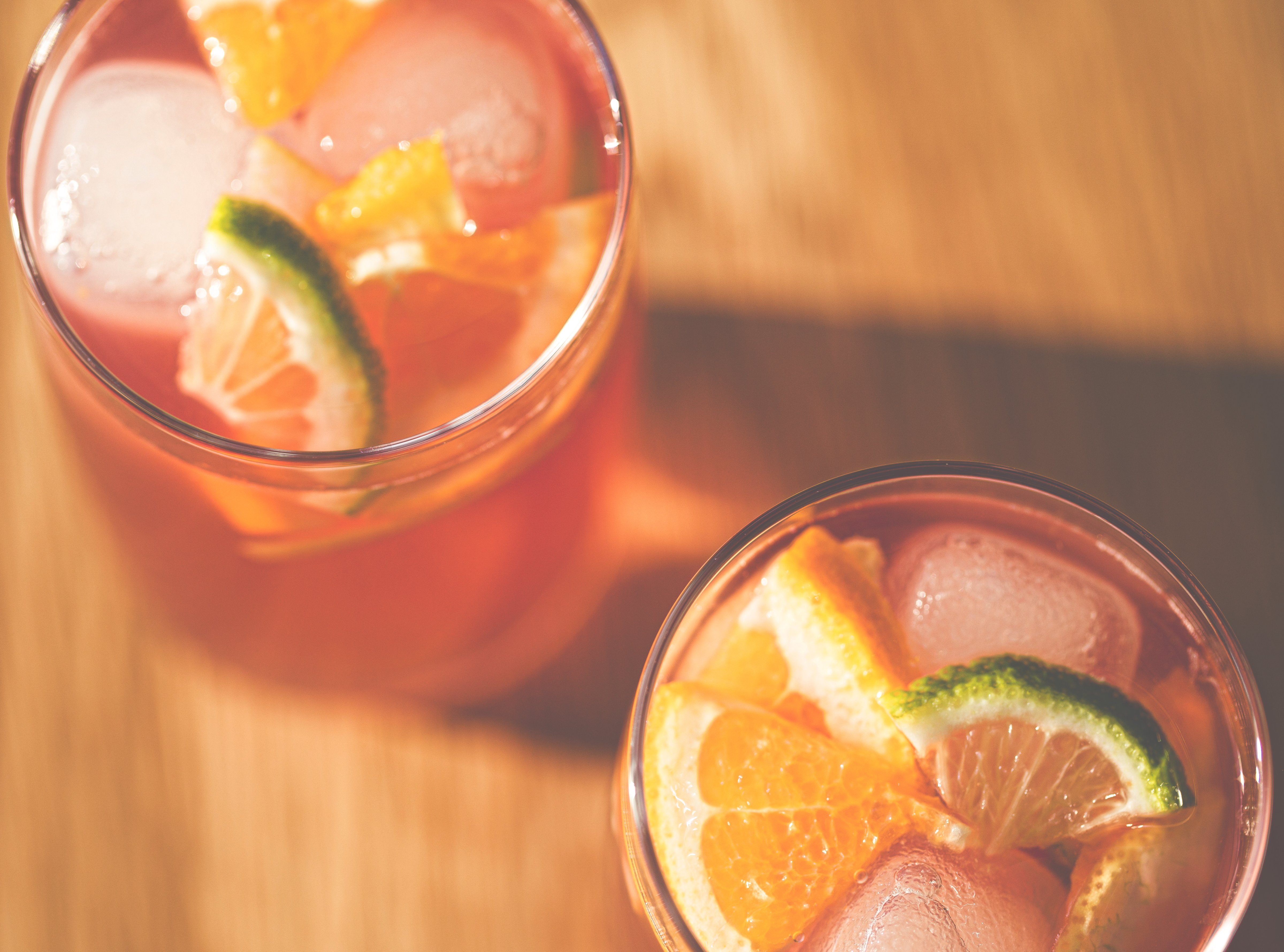 Top down view of 2 glasses of fruity punch with ice cubes and slices of lime and orange. (Getty Images)