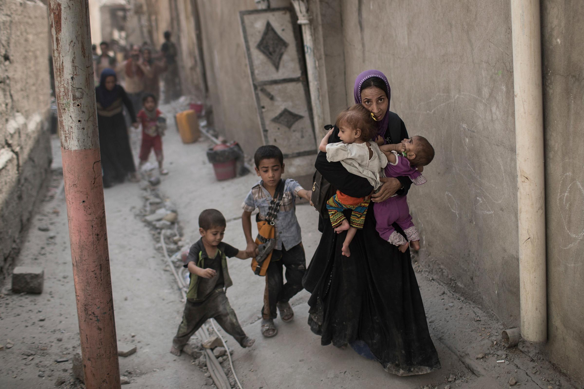 Iraqi civilians flee through an alley as Iraqi Special Forces continue their advance against Islamic State militants in the Old City of Mosul, Iraq, on July 3, 2017.