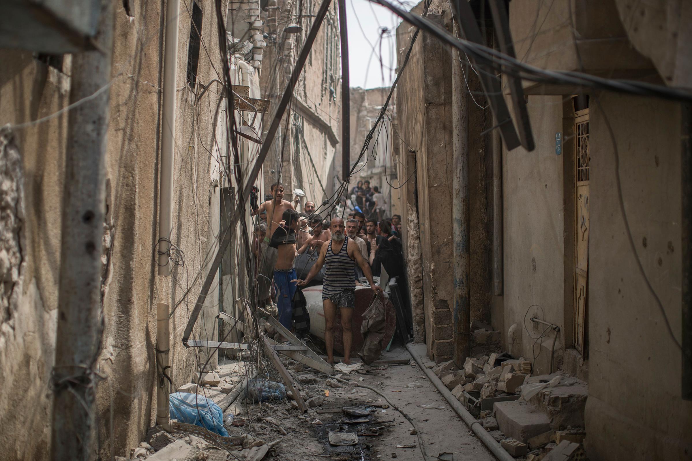 Civilians trying to flee get undressed to be checked for explosives after suicide bombers exploded as Iraqi forces continue their advance against Islamic State militants in the Old City of Mosul, Iraq, on July 3, 2017.