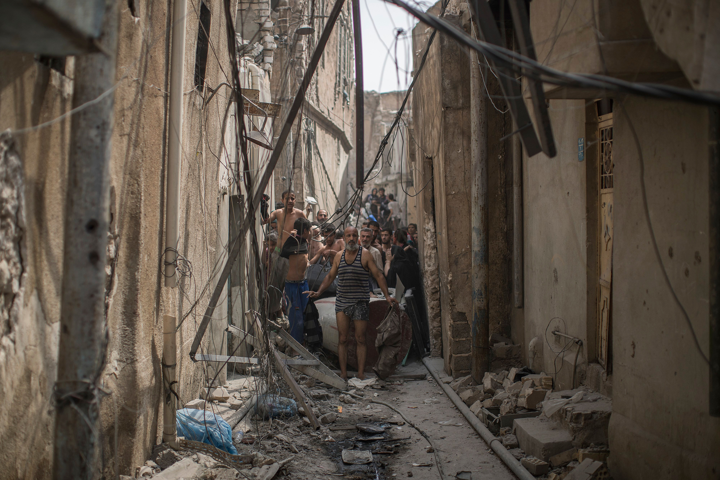 Civilians trying to flee get undressed to be checked for explosives after suicide bombers exploded as Iraqi forces continue their advance against Islamic State militants in the Old City of Mosul, Iraq, on July 3, 2017. (Felipe Dana—AP)