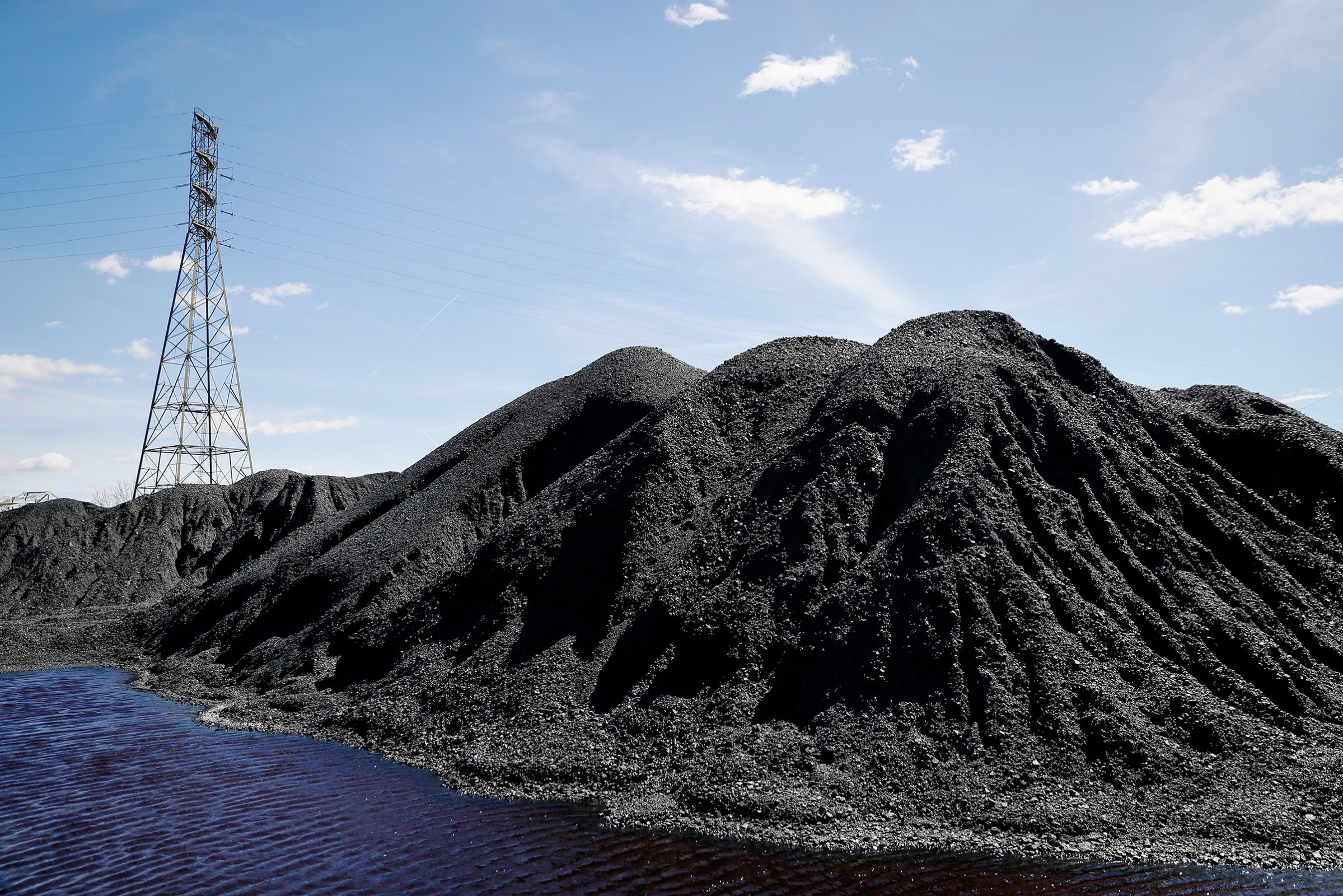 Power lines loom behind piles of coal stored at a facility along the Ohio River in April