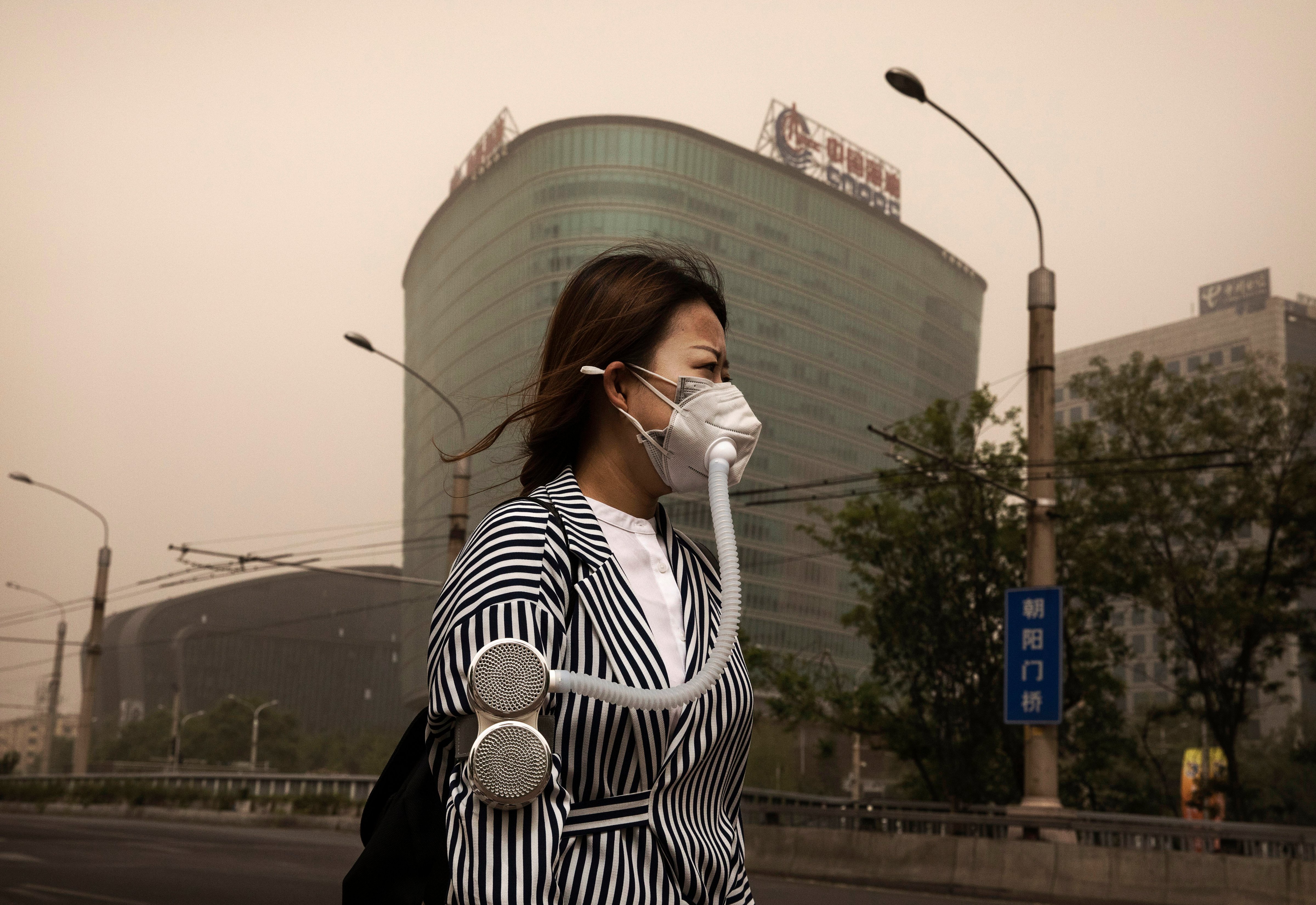 A Chinese woman wears a mask to protect from particles blown in during a sandstorm as she walks in the street on May 4, 2017 in Beijing, China. (Kevin Frayer—Getty Images)