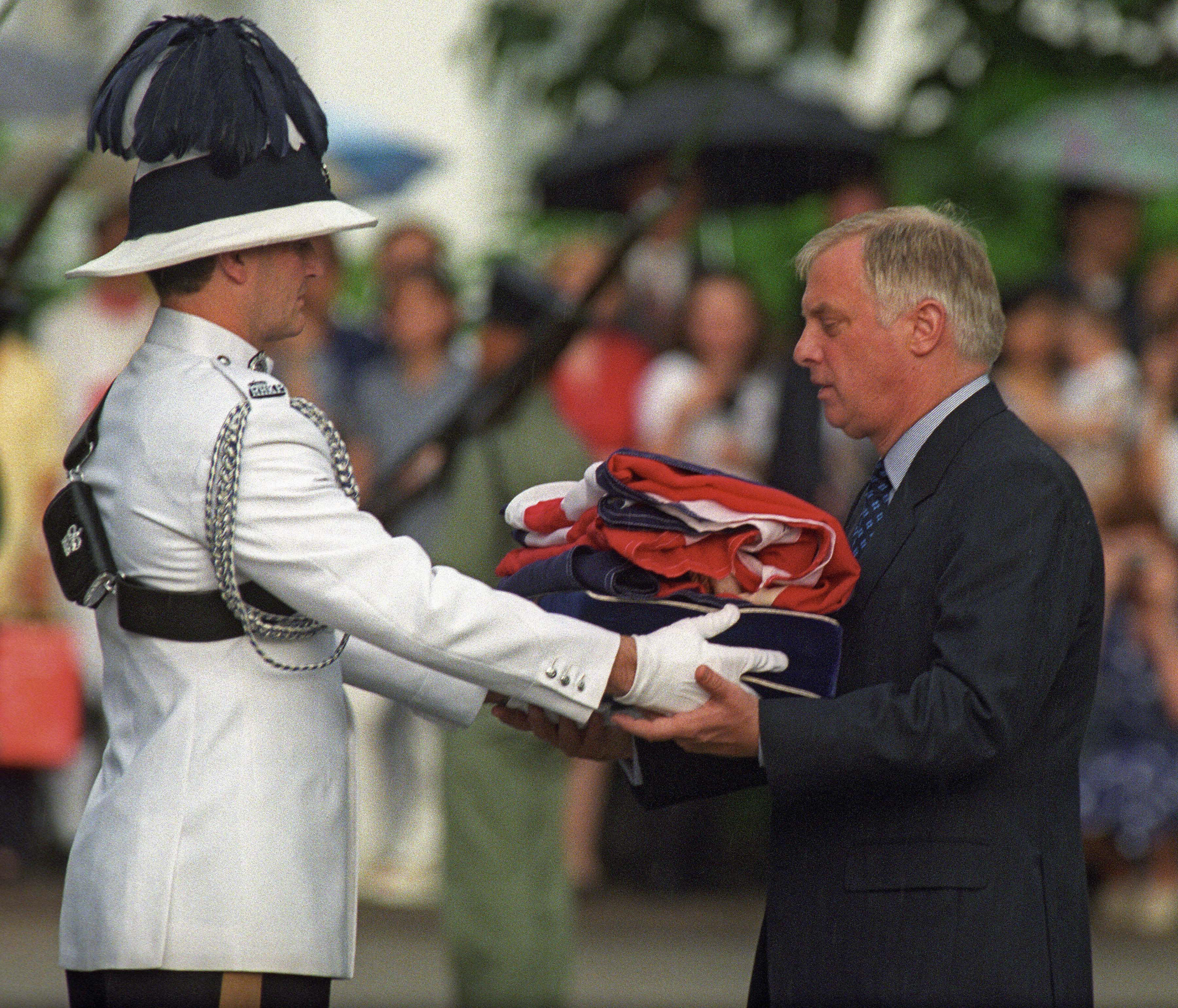Chris Patten (R), the 28th and last governor of colonial Hong Kong, receives the Union Jack flag after is was lowered for the last time at Government House - the governor's official residence - during a farewell ceremony in Hong Kong, 30 June 1997, just hours prior to the end of some 156 years of British colonial rule as the territory returns to Chinese control. (EMMANUEL DUNAND—AFP/Getty Images)