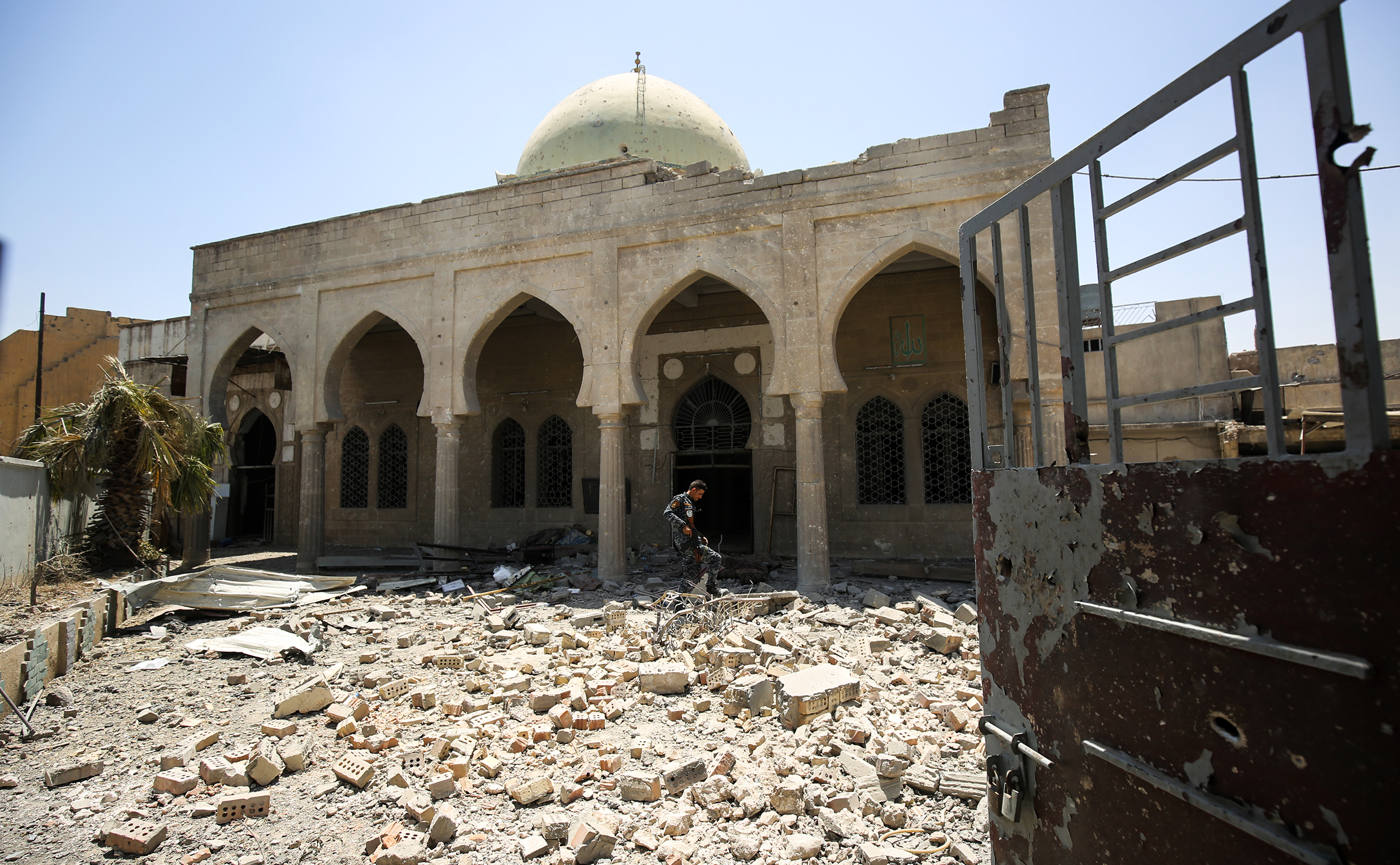 A member of the Iraqi federal police walks through the rubble in the grounds outside the damaged historic 19th century Ziwani mosque in the Old City of Mosul on June 28, 2017, as Iraqi forces inspect damage the building sustained during the offensive to retake the last remaining district from Islamic State (IS) group fighters. (AHMAD AL-RUBAYE—AFP/Getty Images)