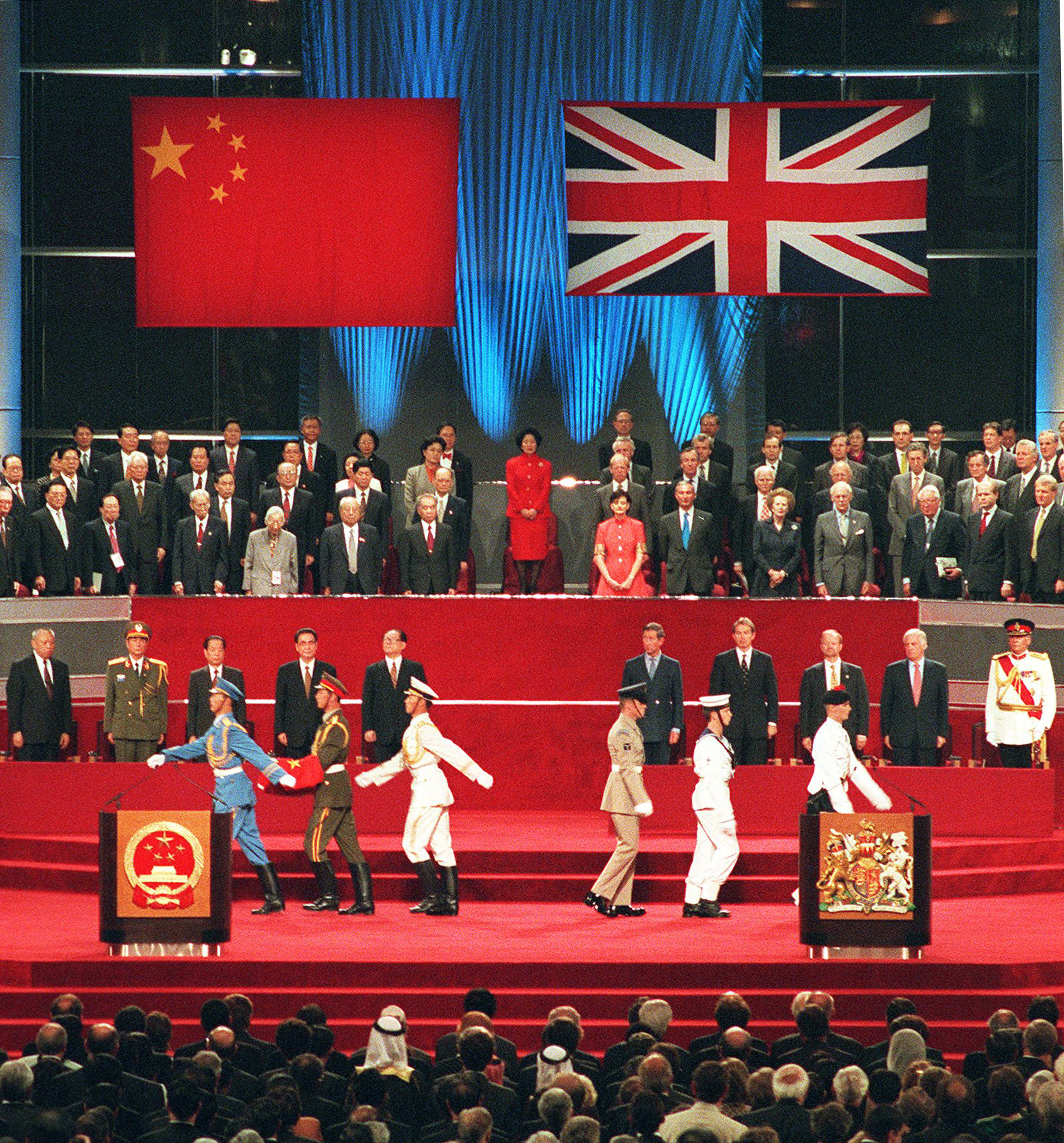 A Chinese soldier holds the national flag prior to its raising as the British military march, at right, during the handover ceremony at the Hong Kong Convention and Exhibition Centre on July 1, 1997. The event marks the end of 156 years of British colonial rule over the territory.
