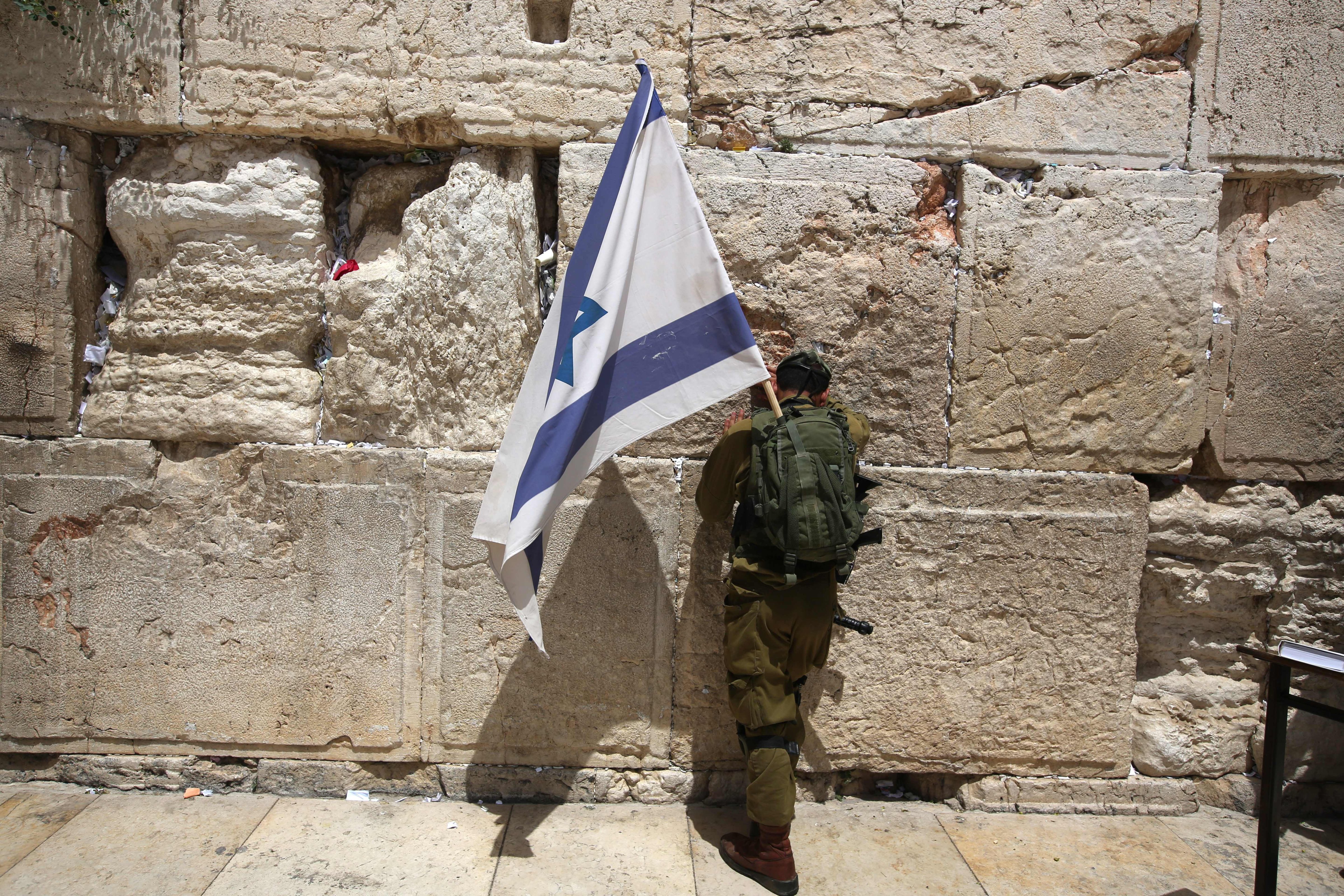 An Israeli soldier prays at the Western Wall with a national flag on June 5, 2016 in Jerusalem's old city, as Israelis celebrate Jerusalem Day. (MENAHEM KAHANA&mdash;AFP/Getty Images)
