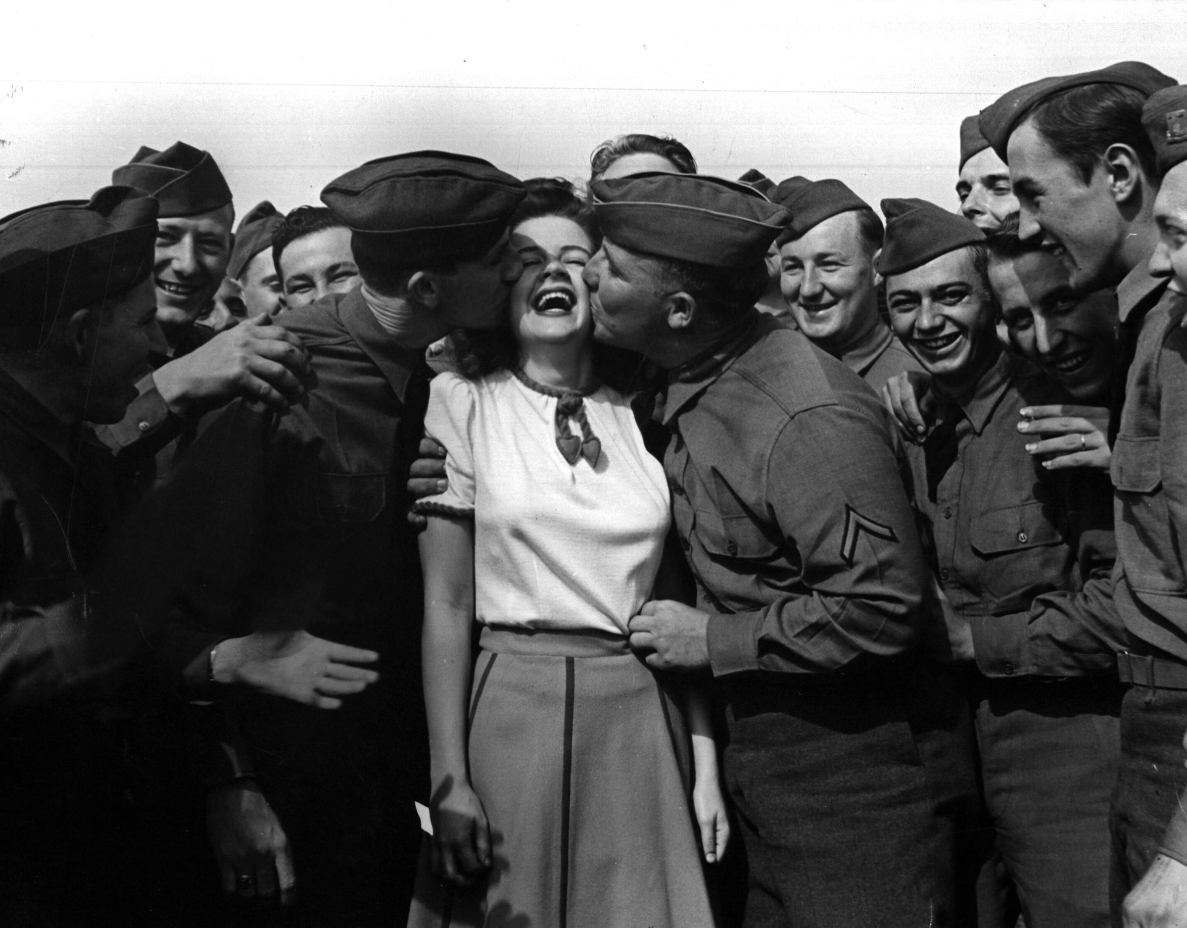 Actress Marilyn Hare being kiss by soldiers as repayment, 1942.