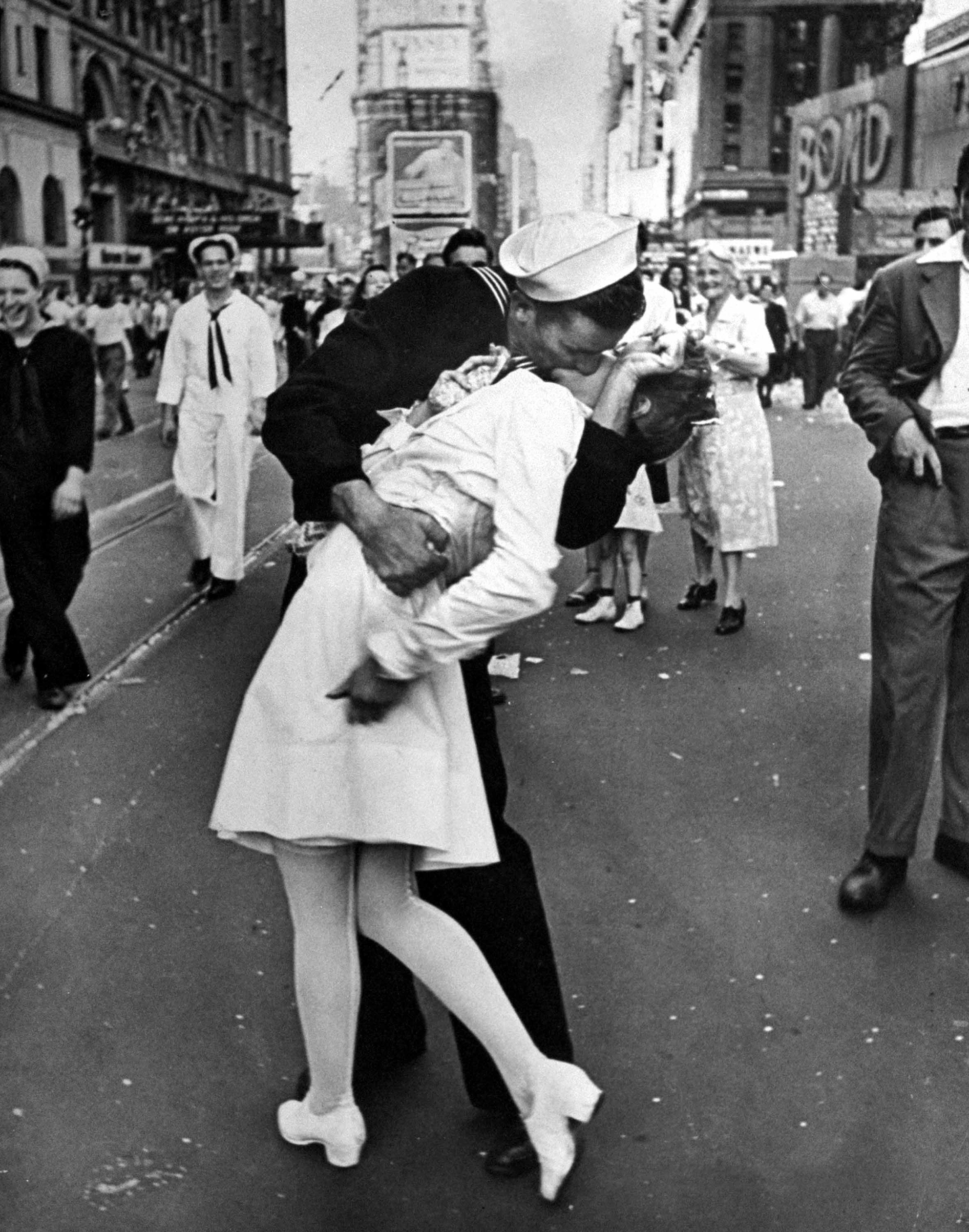 A jubilant American sailor clutching a nurse in a back-bending, passionate kiss as he vents his joy while thousands jam the Times Square area to celebrate the long awaited victory over Japan. 1945.