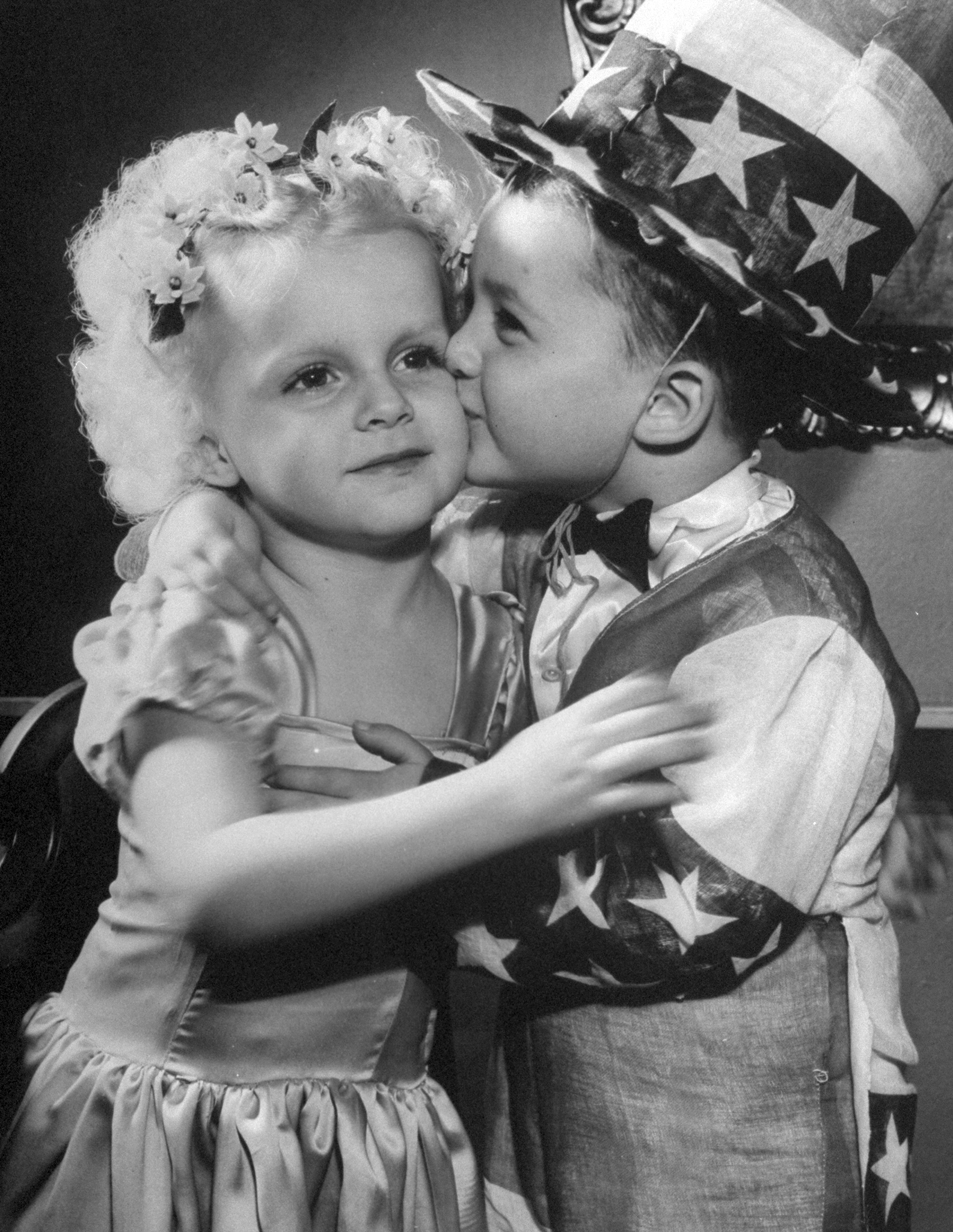 A little boy dressed as Uncle Sam, kissing a little girl on the cheek.1945.