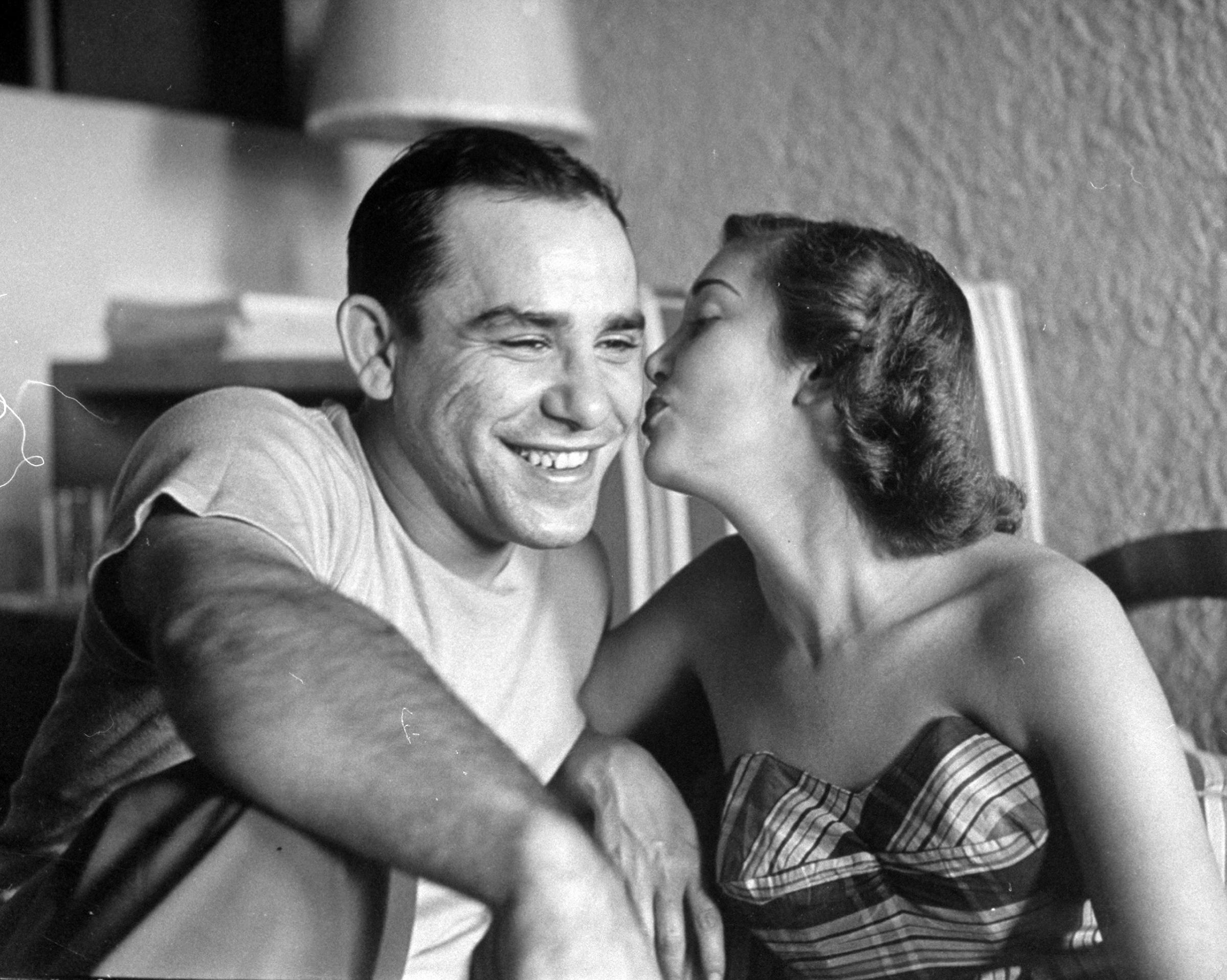Baseball player Yogi Berra getting kiss from his wife, Carmen, before he leaves for clubhouse. 1949.