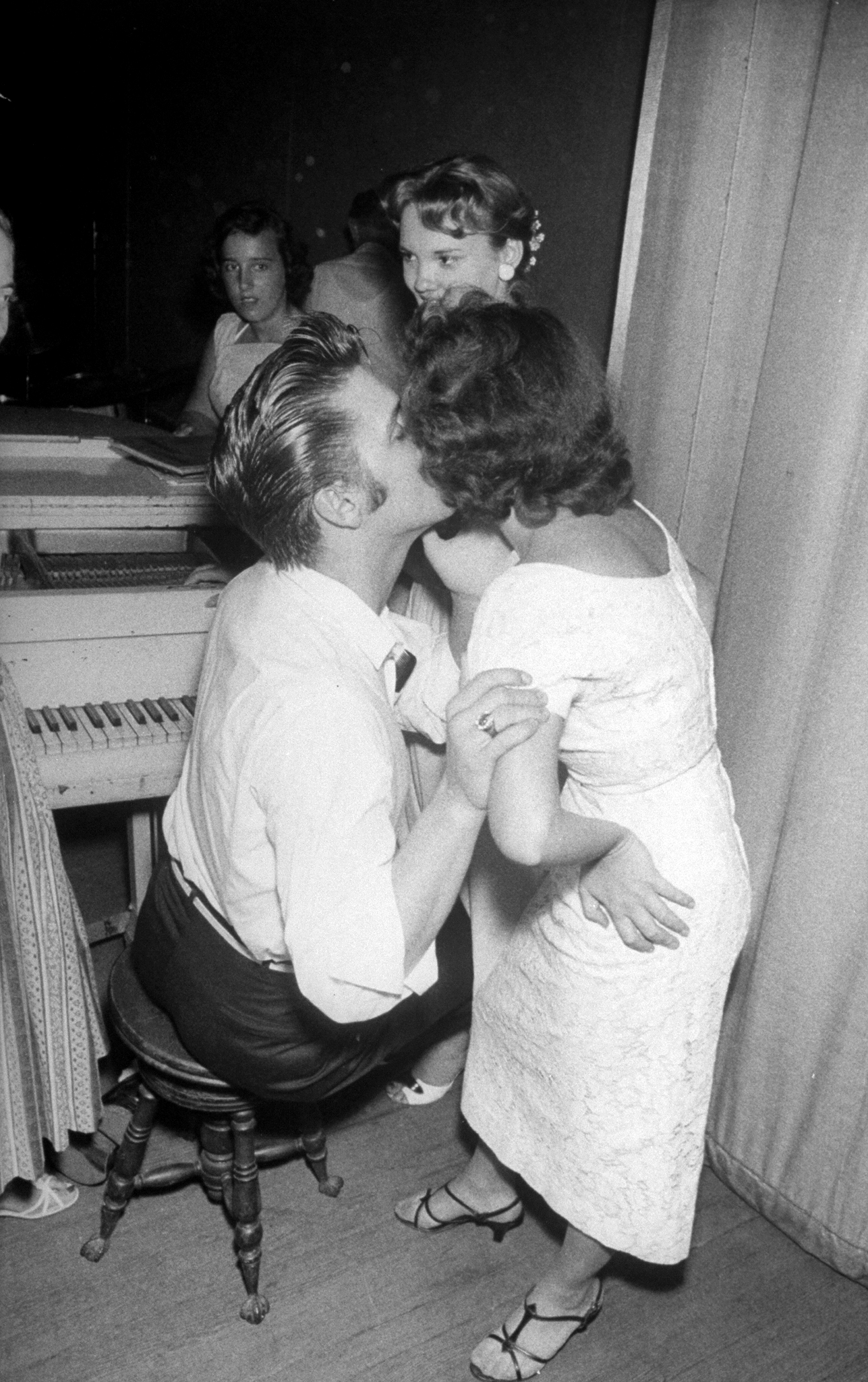 Elvis Presley tenderly embracing and kissing the cheek of a female admirer backstage before his concert, 1956.
