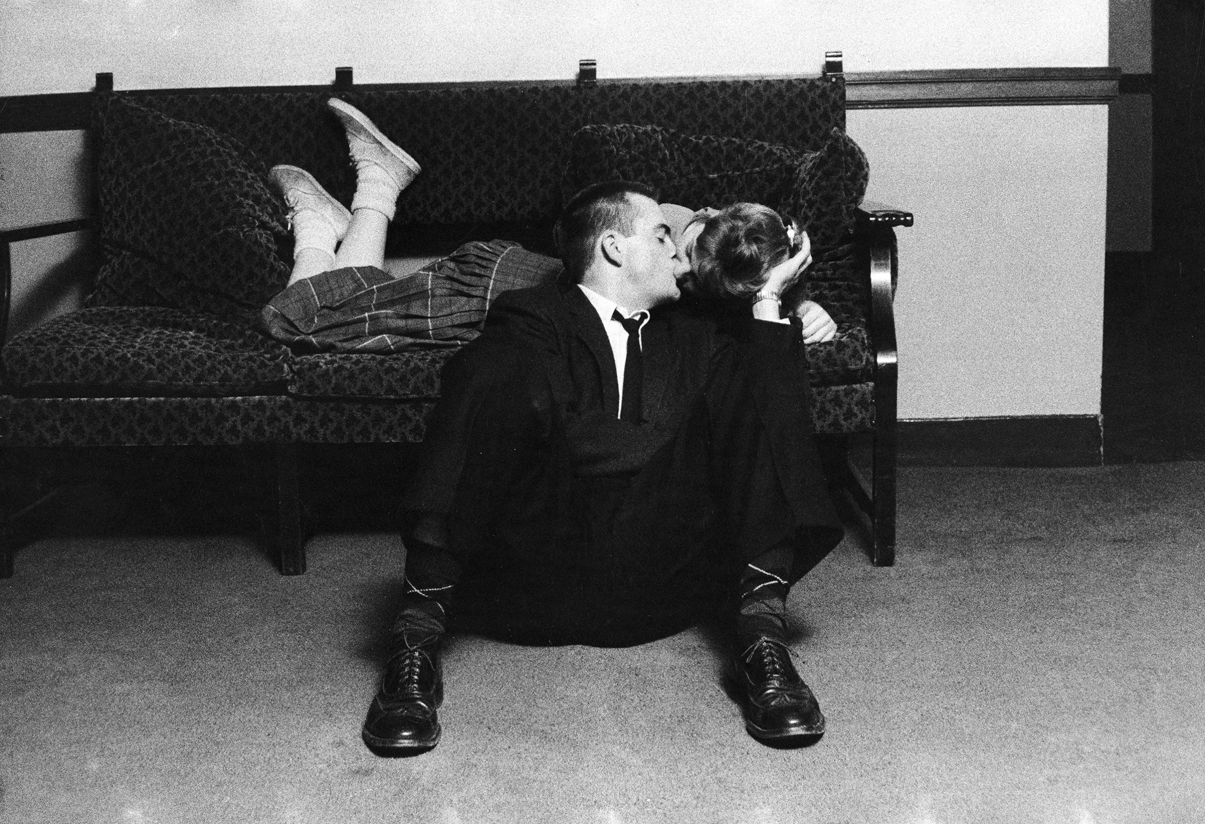 University of Michigan student couple engaged in an impromptu kiss, which was forbidden conduct even before school ban, because earlier rules required couples to have both feet on the floor, in the Union Building on campus. 1957.