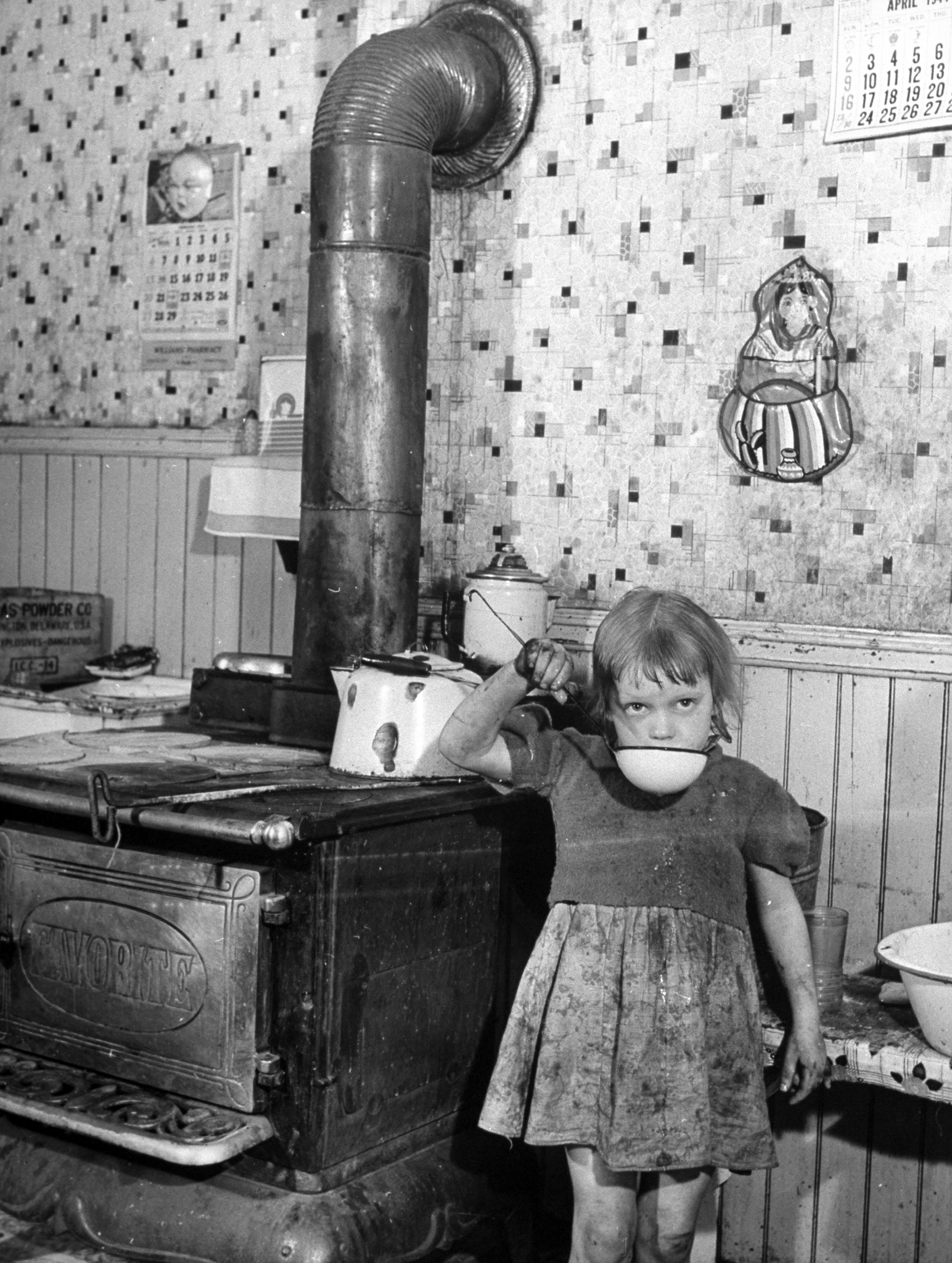 A little girl drinking water in a the dirty kitchen of a steel worker's family in Pittsburgh.