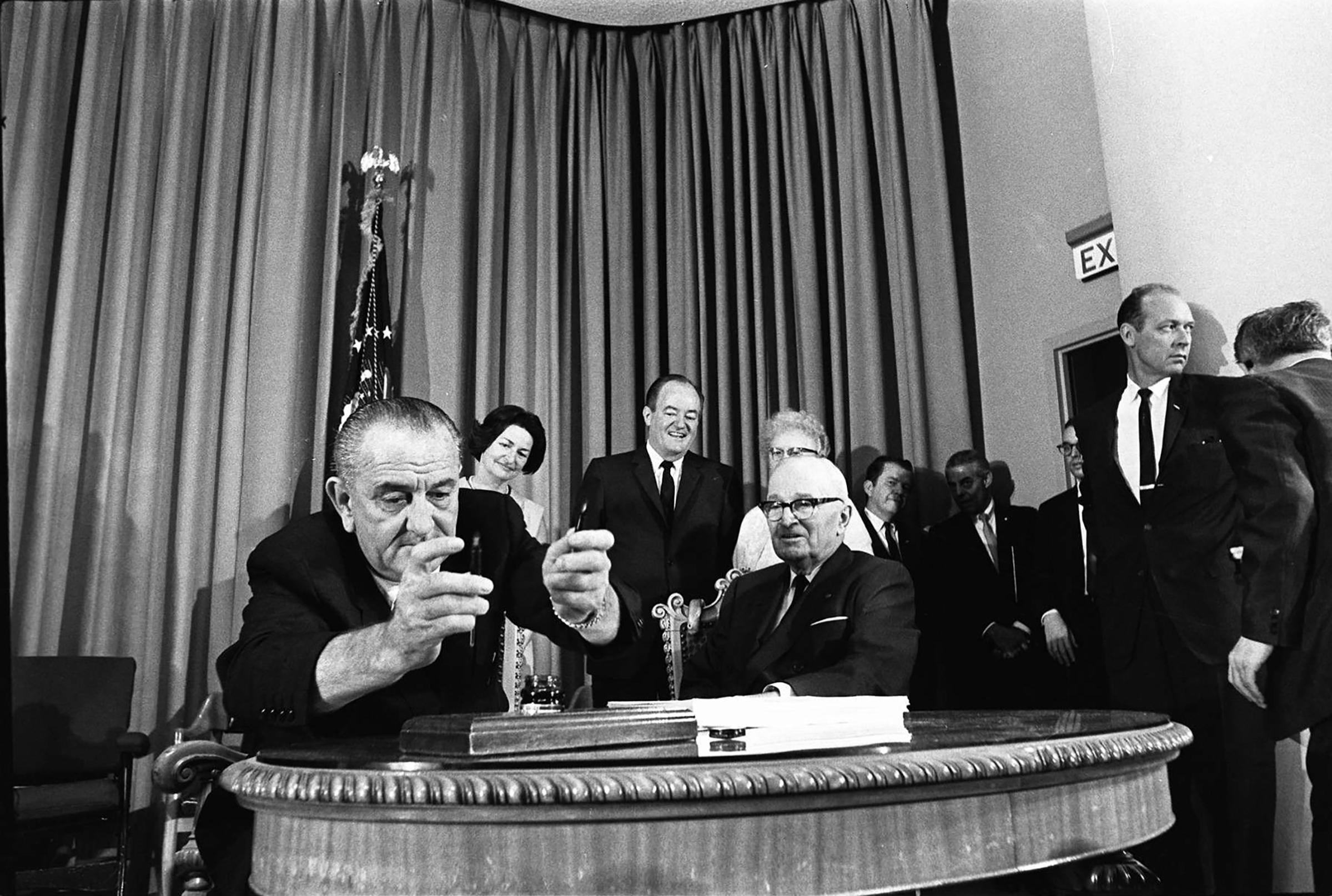 President Lyndon Johnson signs legislation creating Medicare and Medicaid in 1965.
