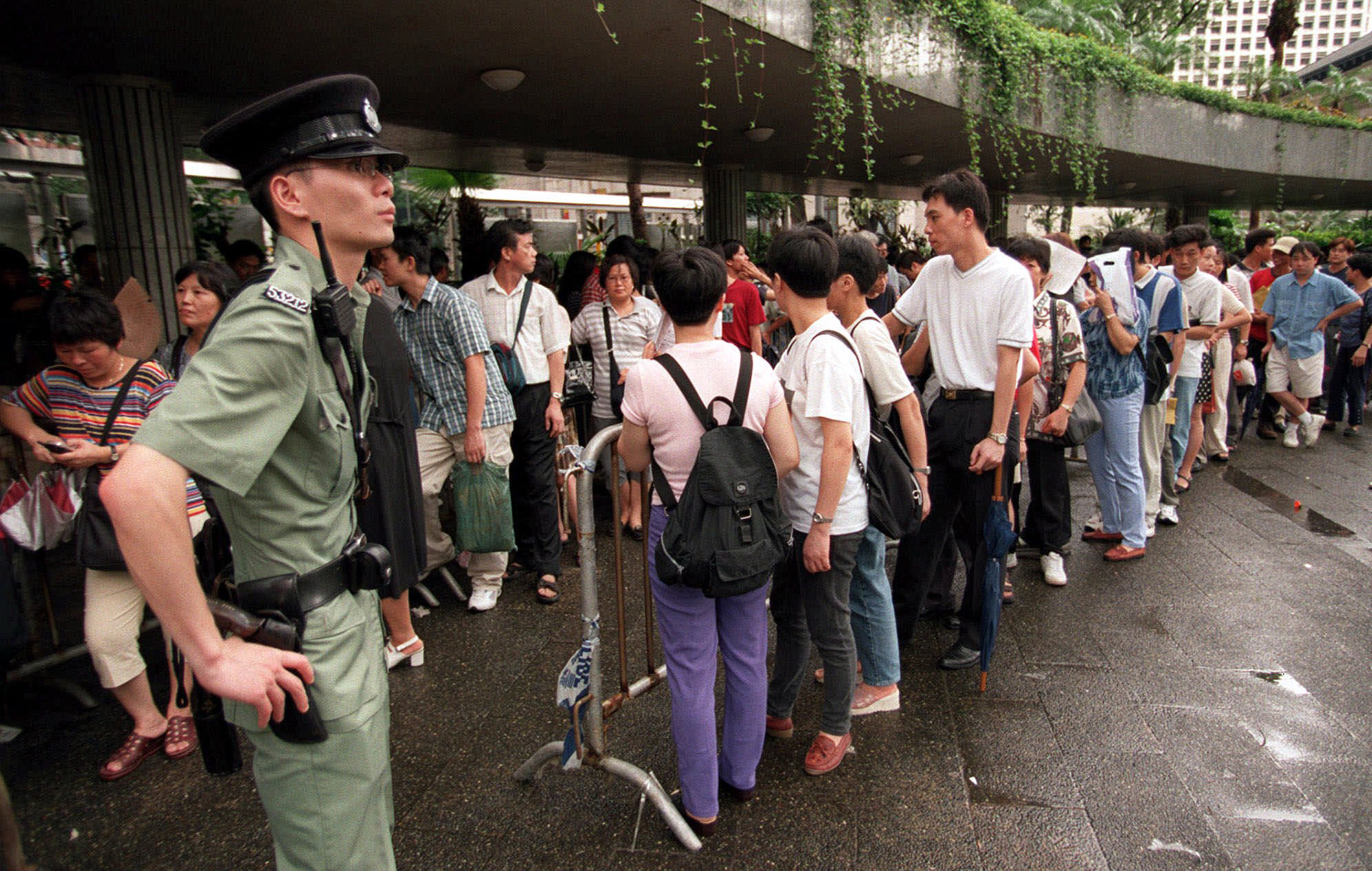 Mainland Chinese immigrants line up outside Hong Kong's Legislative Council building on July 8, 1999, to register their information to appeal for their residency rights in Hong Kong after the People's National Congress in Beijing provided a new interpretation of the Basic law. A Chief Judge admitted recent events in the right-of-abode affair had created confusion and he was unable to deal with a case of a mainland-born woman claiming the right to stay, the first to come before the court of Appeals since the re-interpretation of the Basic Law.