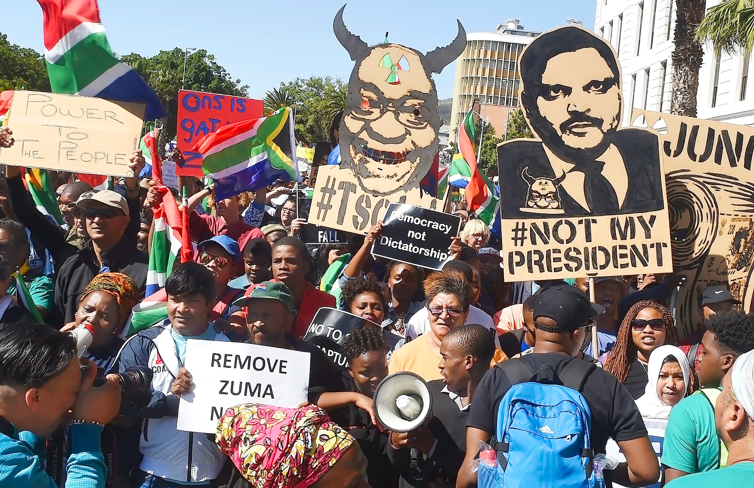 A placard depicting Atul Gupta, right, 
                      is seen at an anti-Zuma protest in April (Xabiso Mkhabela—Anadolu Agency/Getty Images)