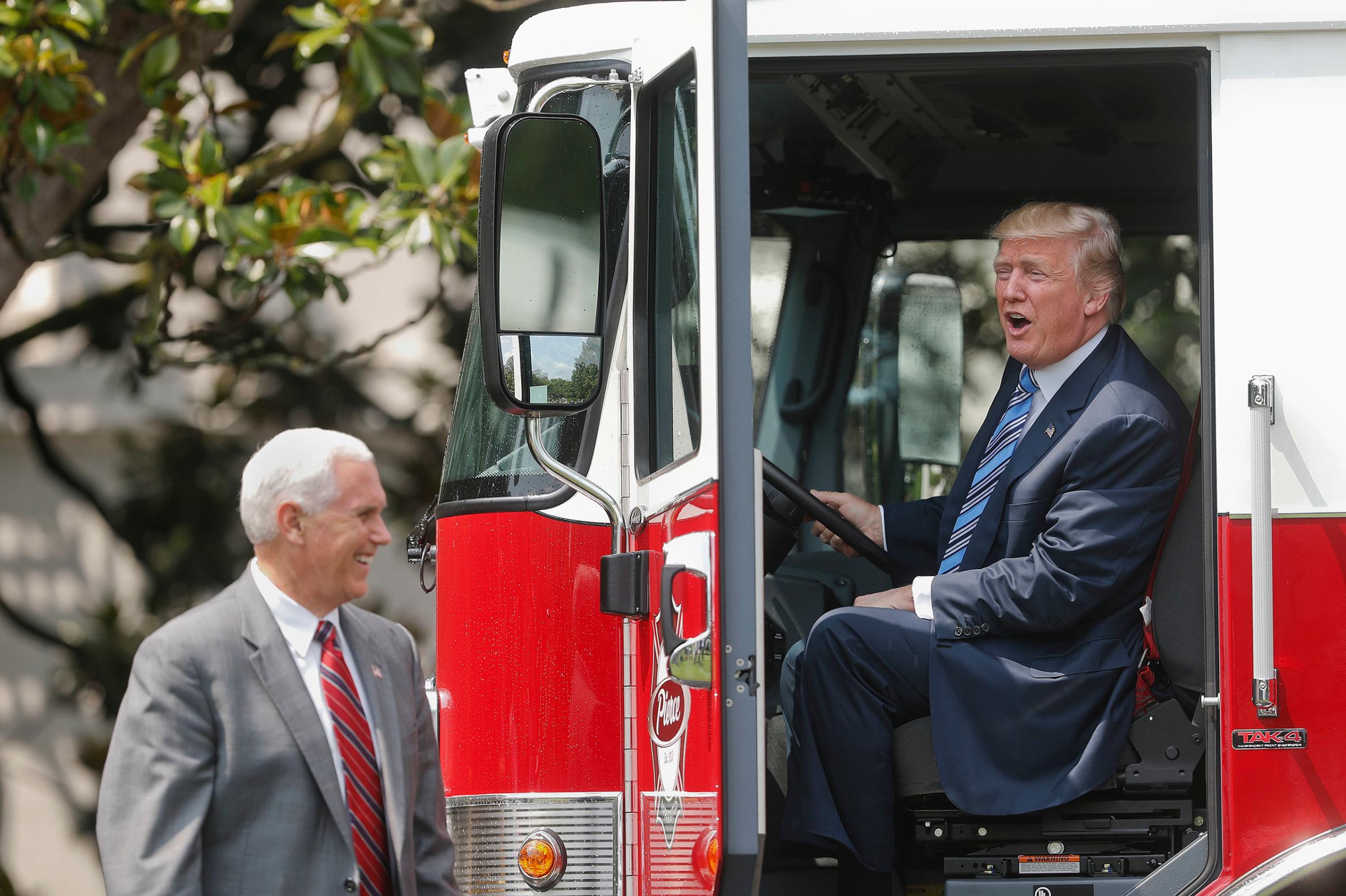 President Donald Trump, accompanied by Vice President Mike Pence, sits inside a cabin of a firetruck during a "Made in America," product showcase featuring items created in each of the U.S. 50 states, Monday, July 17, 2017, on the South Lawn of the White House in Washington.
