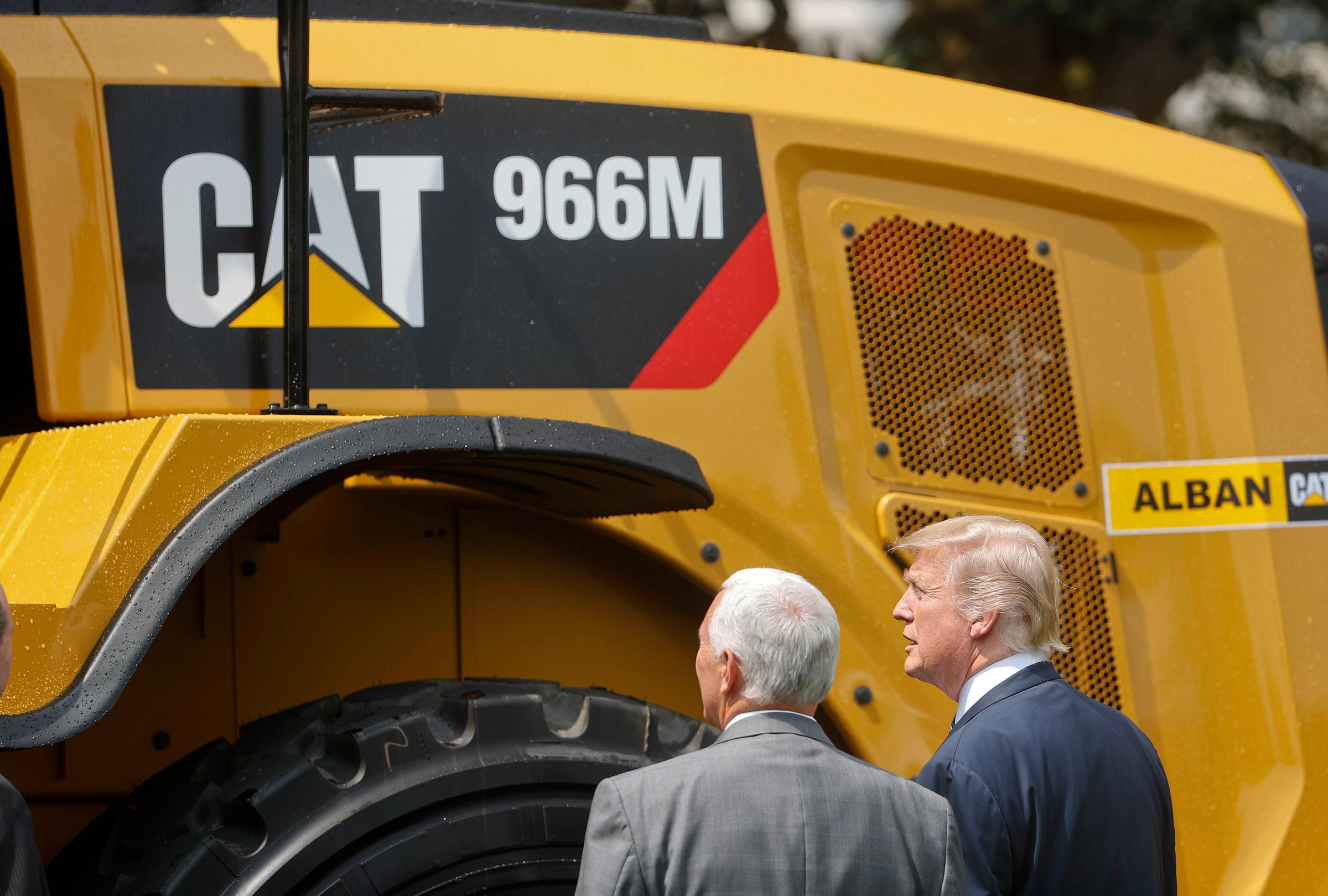 President Donald Trump and Vice President Mike Pence stop to looks at a Caterpillar truck, manufactured in Illinois, on the South Lawn of the White House in Washington, Monday, July 17, 2017, during a "Made in America," product showcase featuring items created in each of the U.S. 50 states.