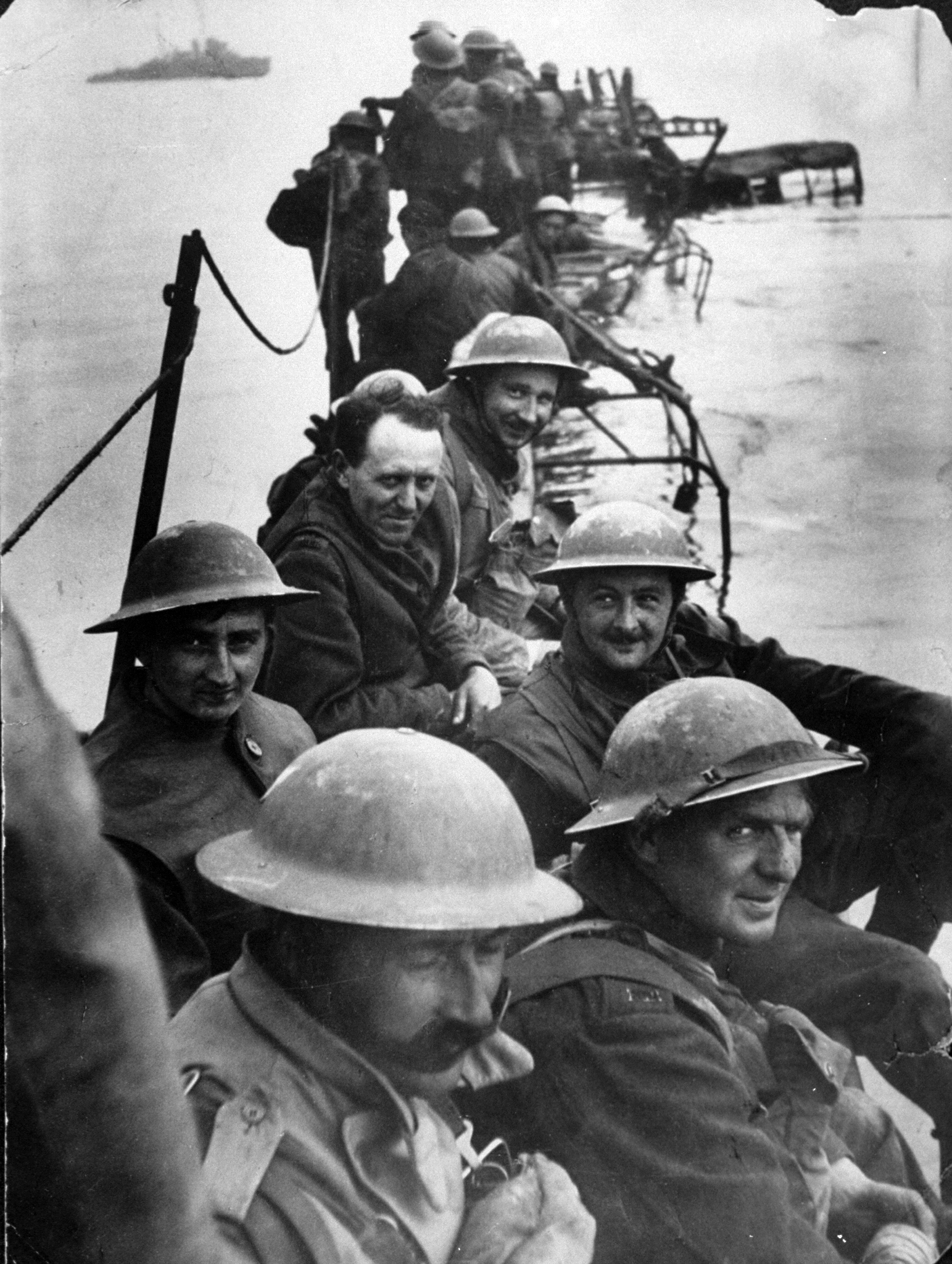 Members of Royal Ulster Rifles waiting on improvised pier of lorries to evacuate Dunkirk during low tide.