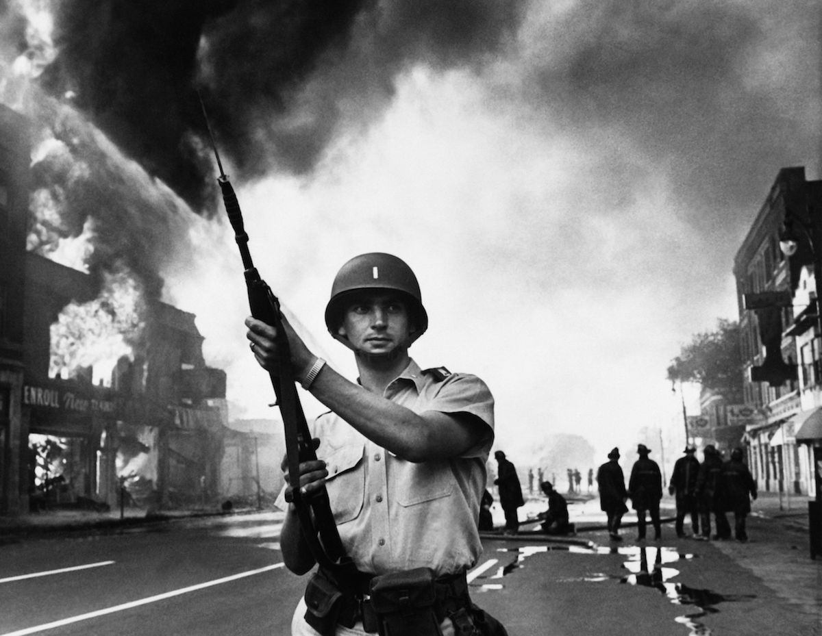 A federal soldier stands guard in a Detroit street on July 25, 1967, as buildings are burning during riots that erupted in Detroit following a police operation (AFP/Getty Images)