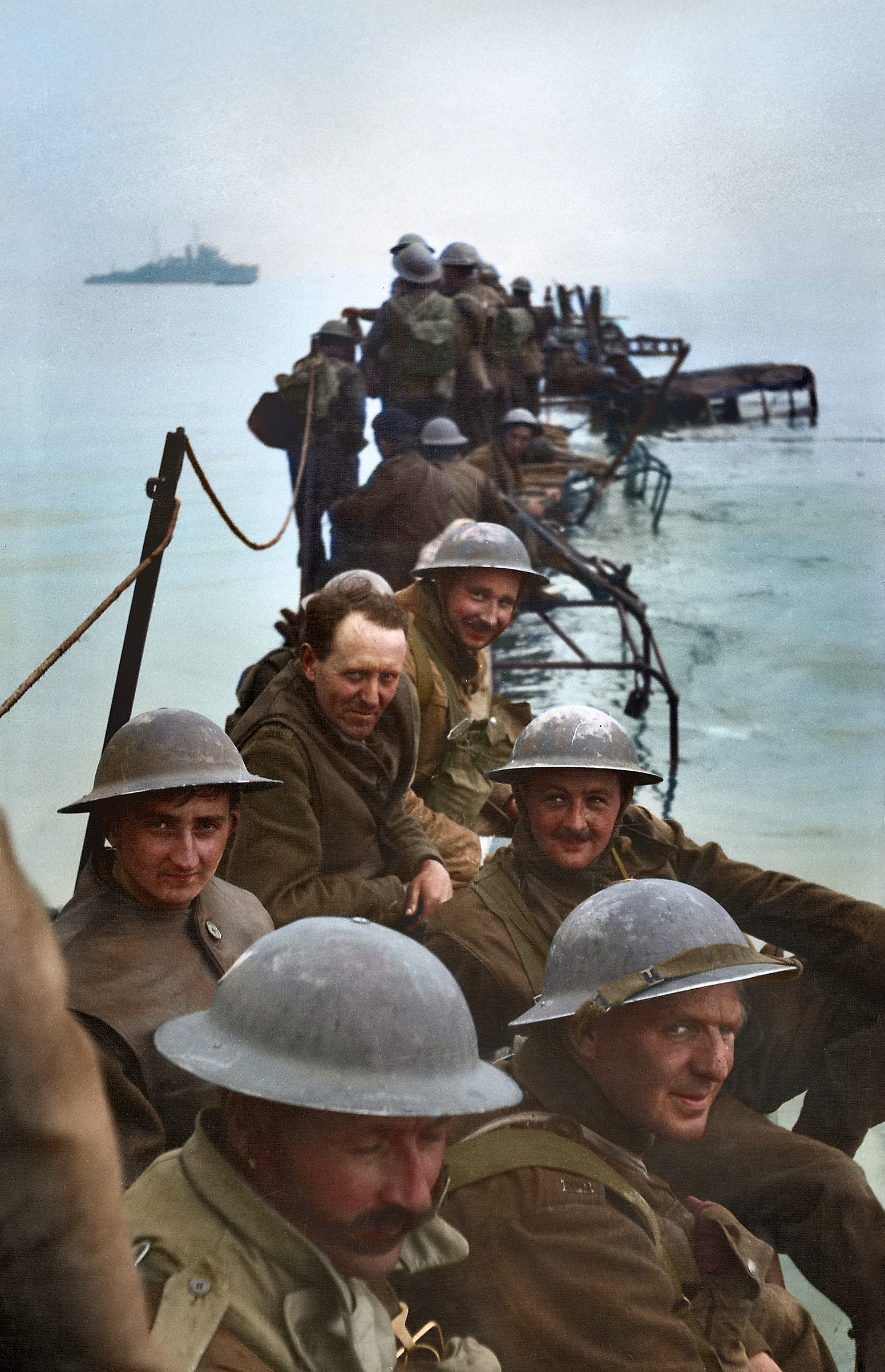 Members of Royal Ulster Rifles waiting on improvised pier of lorries to evacuate Dunkirk during low tide.