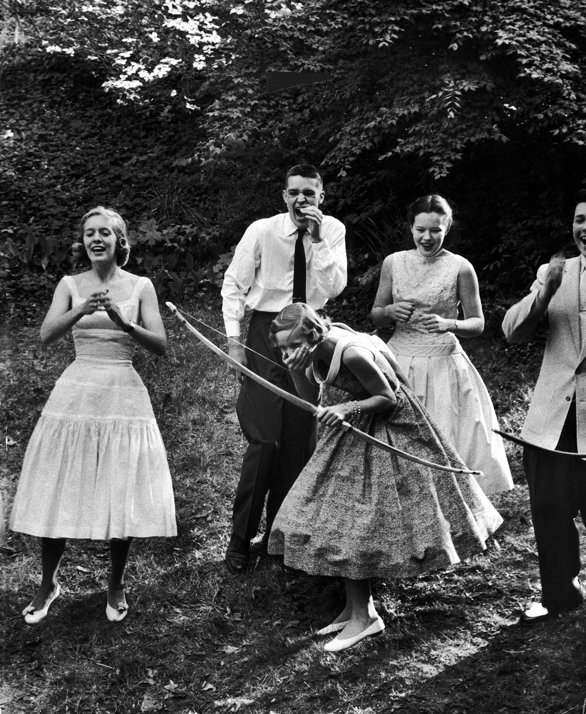 Archery providing entertainment for a group of friends at a teenage party, 1956.
