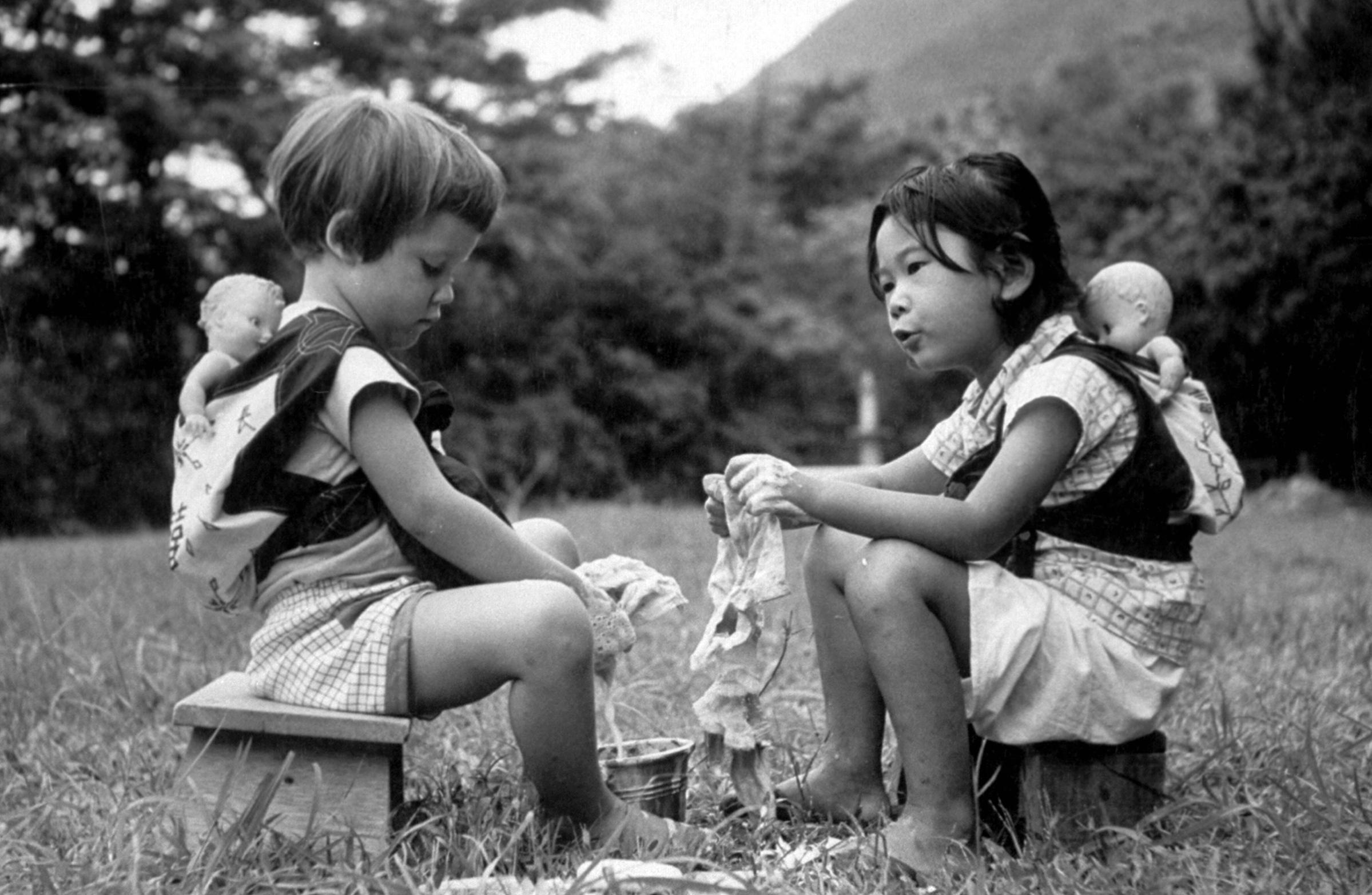 Two young girls playing and washing their doll clothes, 1957.