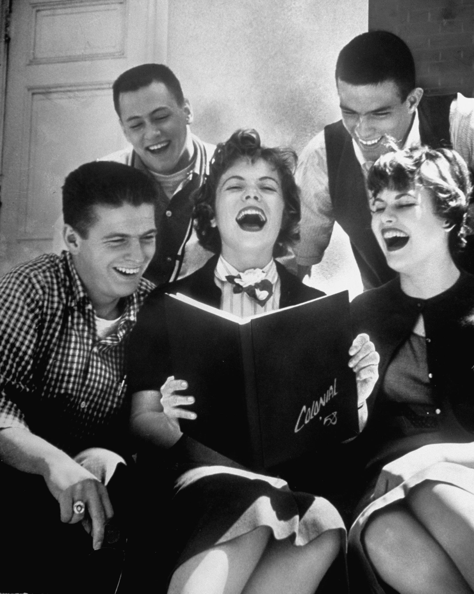 Hempstead High School seniors roaring with laughter as they look over pictures in their newly published yearbook, 1958.