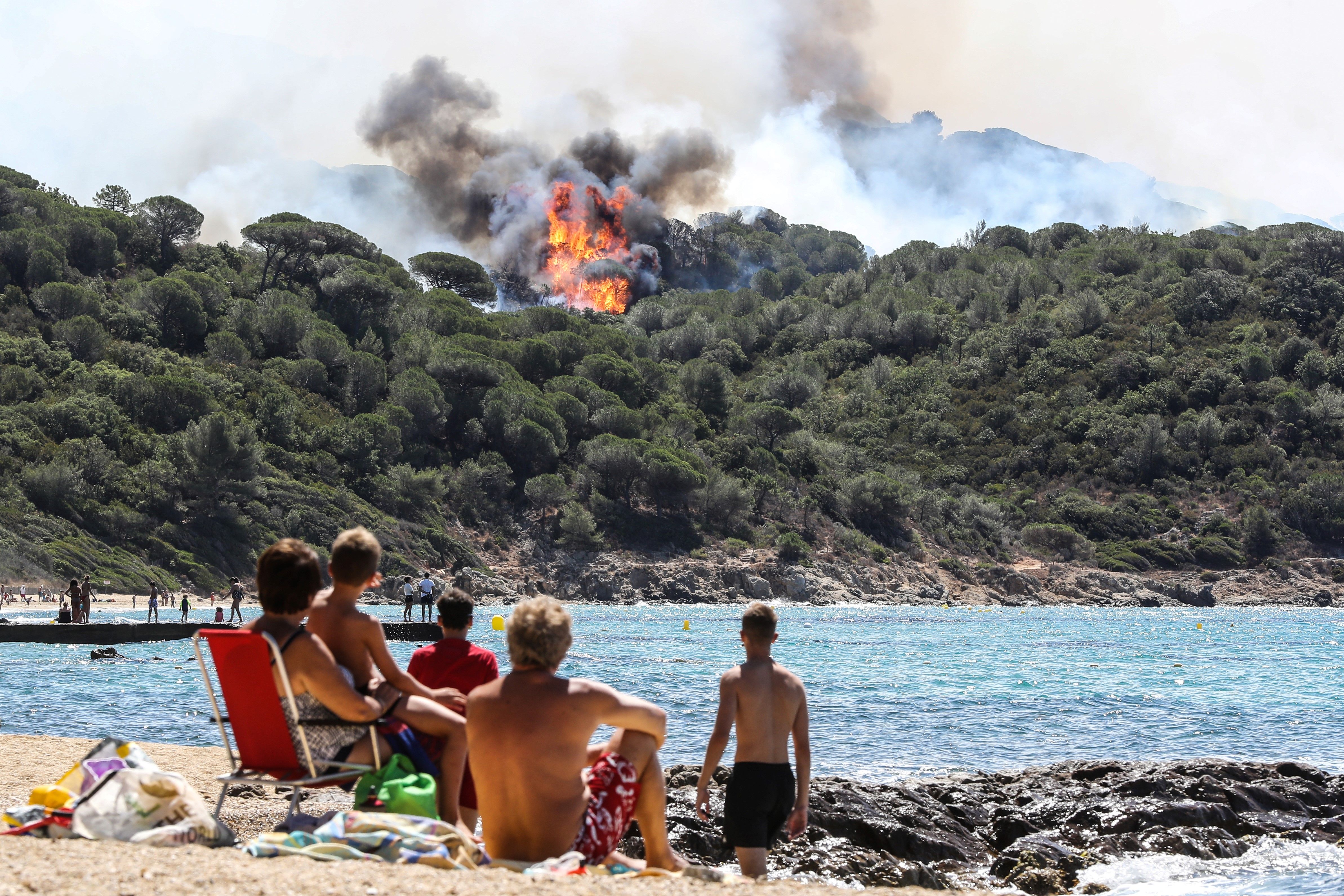People enjoy the beach as they look at a forest fire in La Croix-Valmer, near Saint-Tropez, France, July 25, 2017. (Valery Hache—AFP/Getty Images)